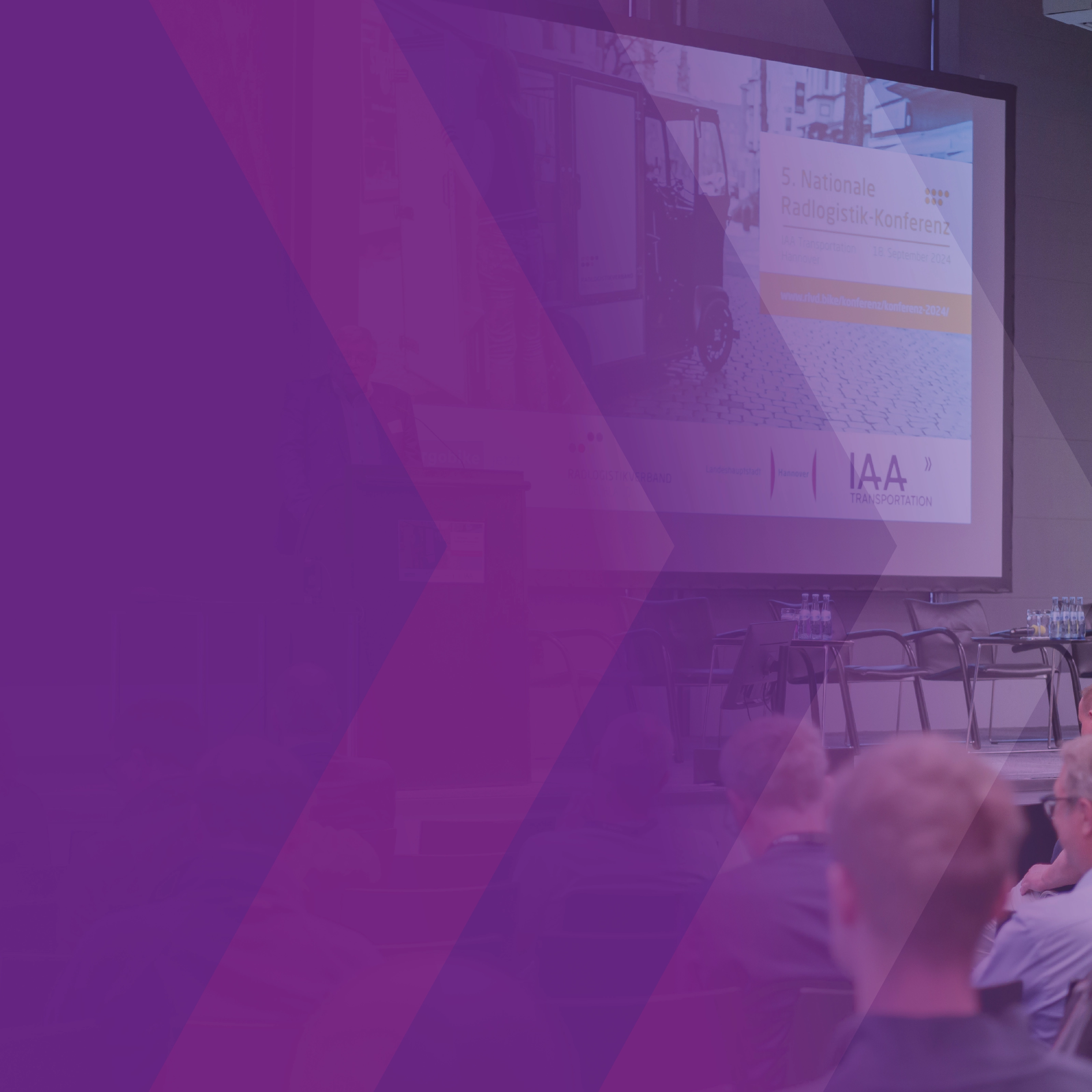 Audience seated before a stage with a presentation screen at a logistics conference.