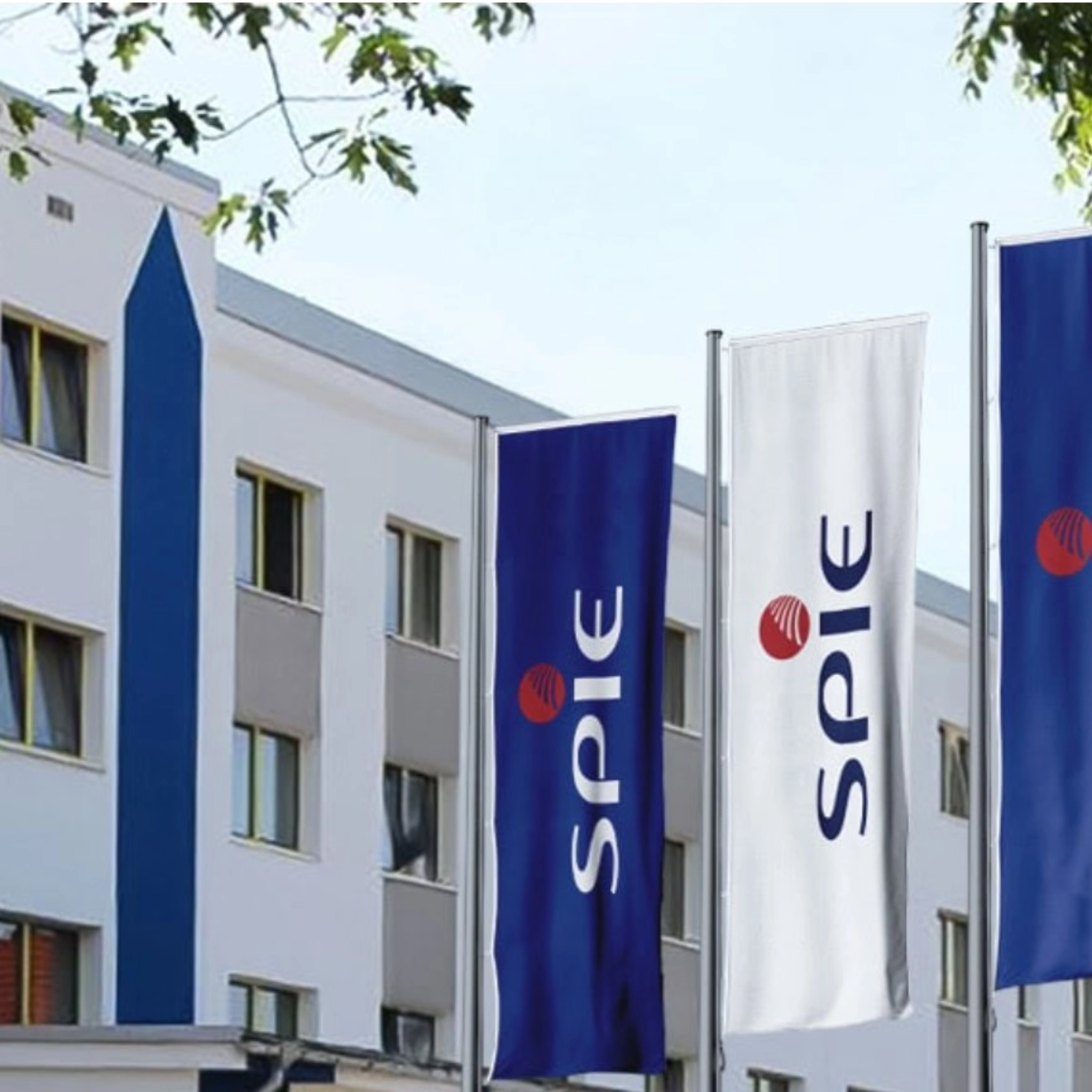 SPIE-Gebäude mit mehreren blauen SPIE-Flaggen an der Fassade.