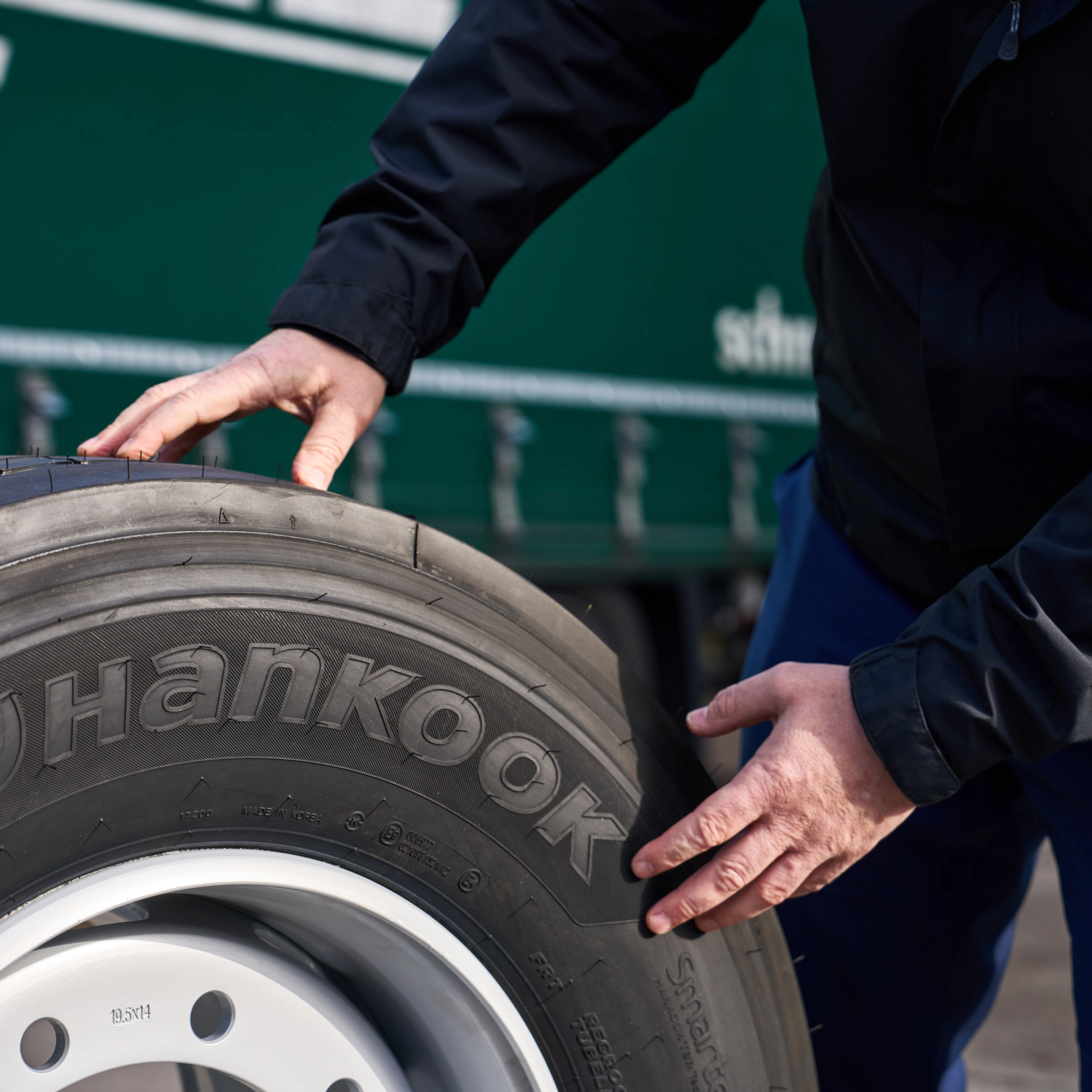Hände prüfen einen Hankook-Lkw-Reifen auf einer Felge.