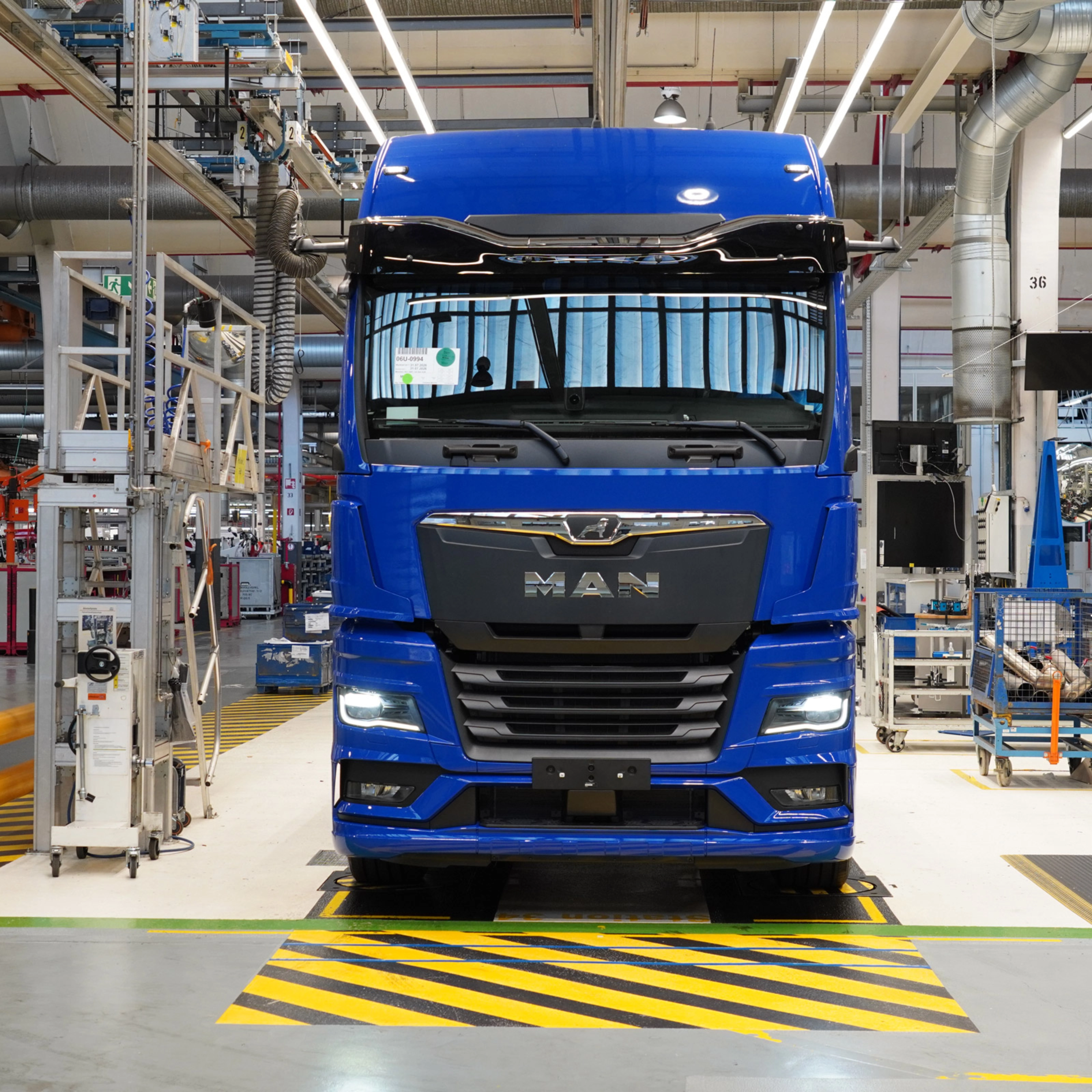 Blauer MAN-Lkw auf einer Produktionslinie in einer modernen Fertigungshalle.