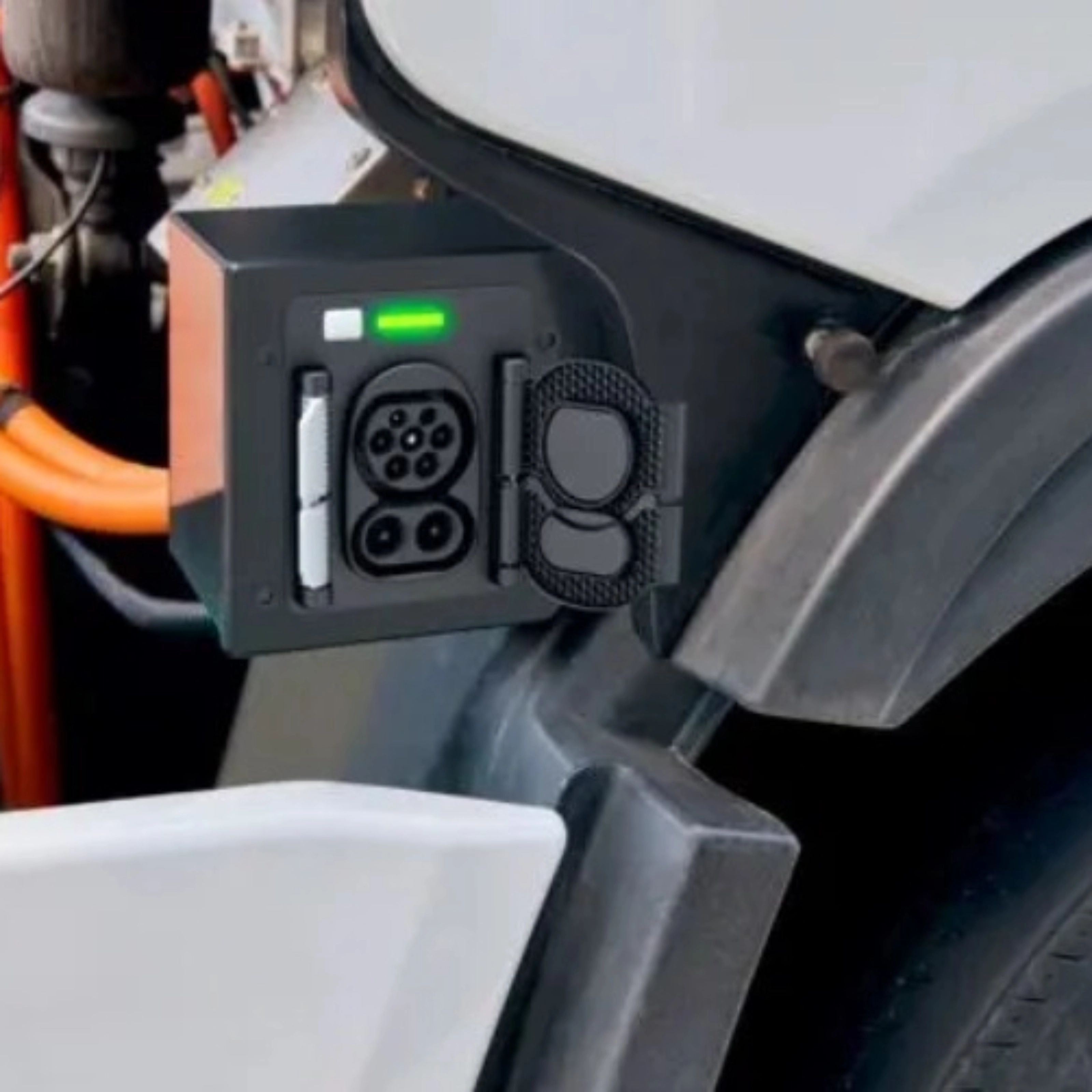 Charging port of an electric truck with visible high-voltage cables and a green status light.