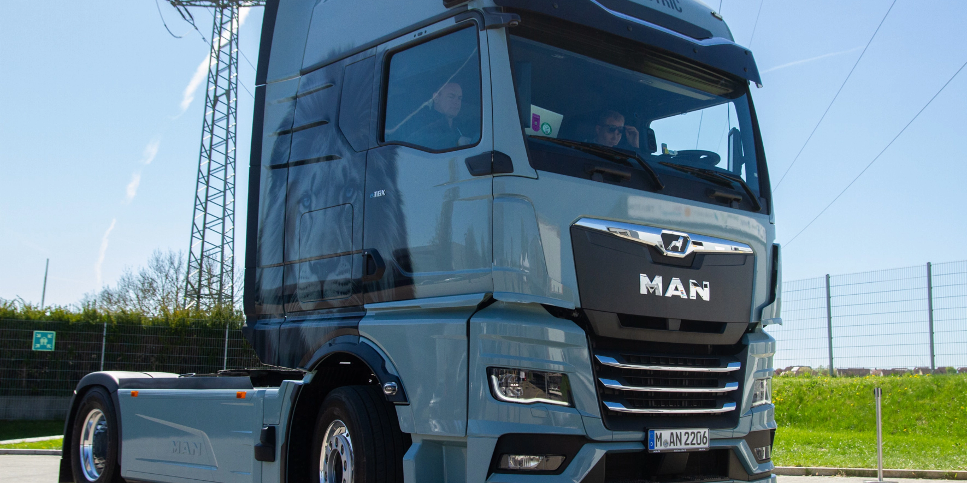 Light blue MAN truck in three-quarter front view on an open road.