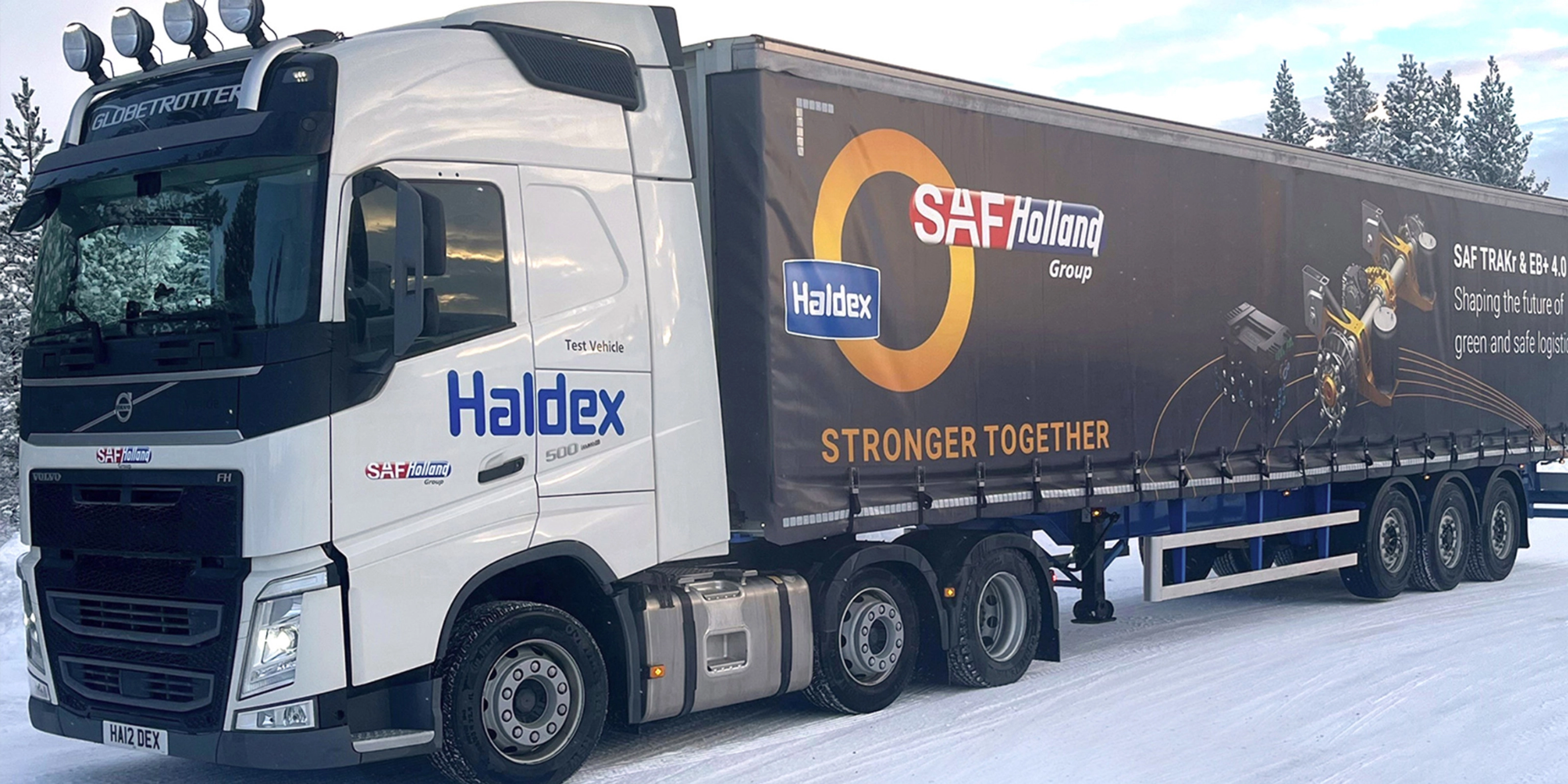 SAF-Holland truck with trailer driving on a snow-covered road.