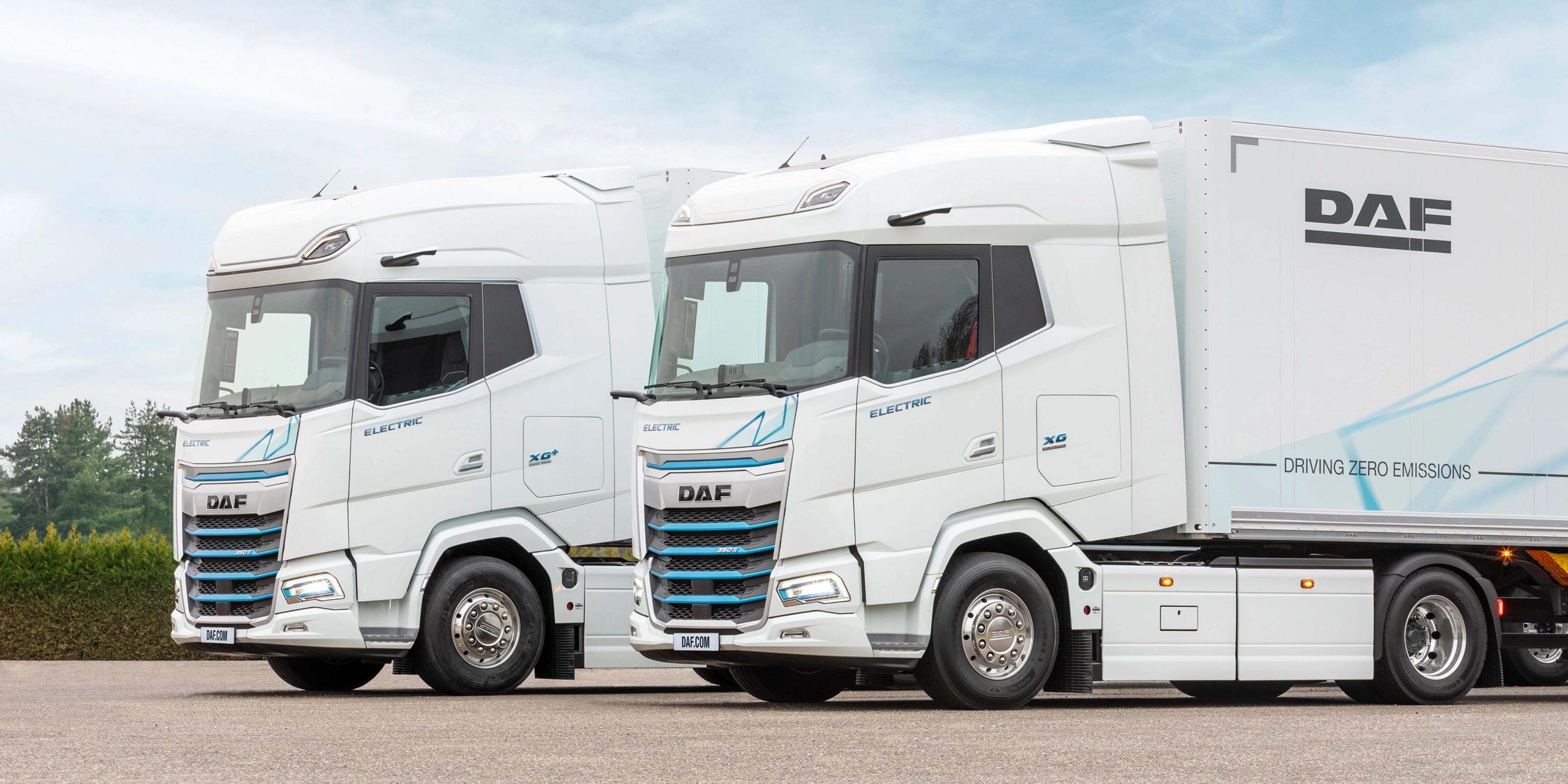Two DAF electric trucks parked side by side outdoors.