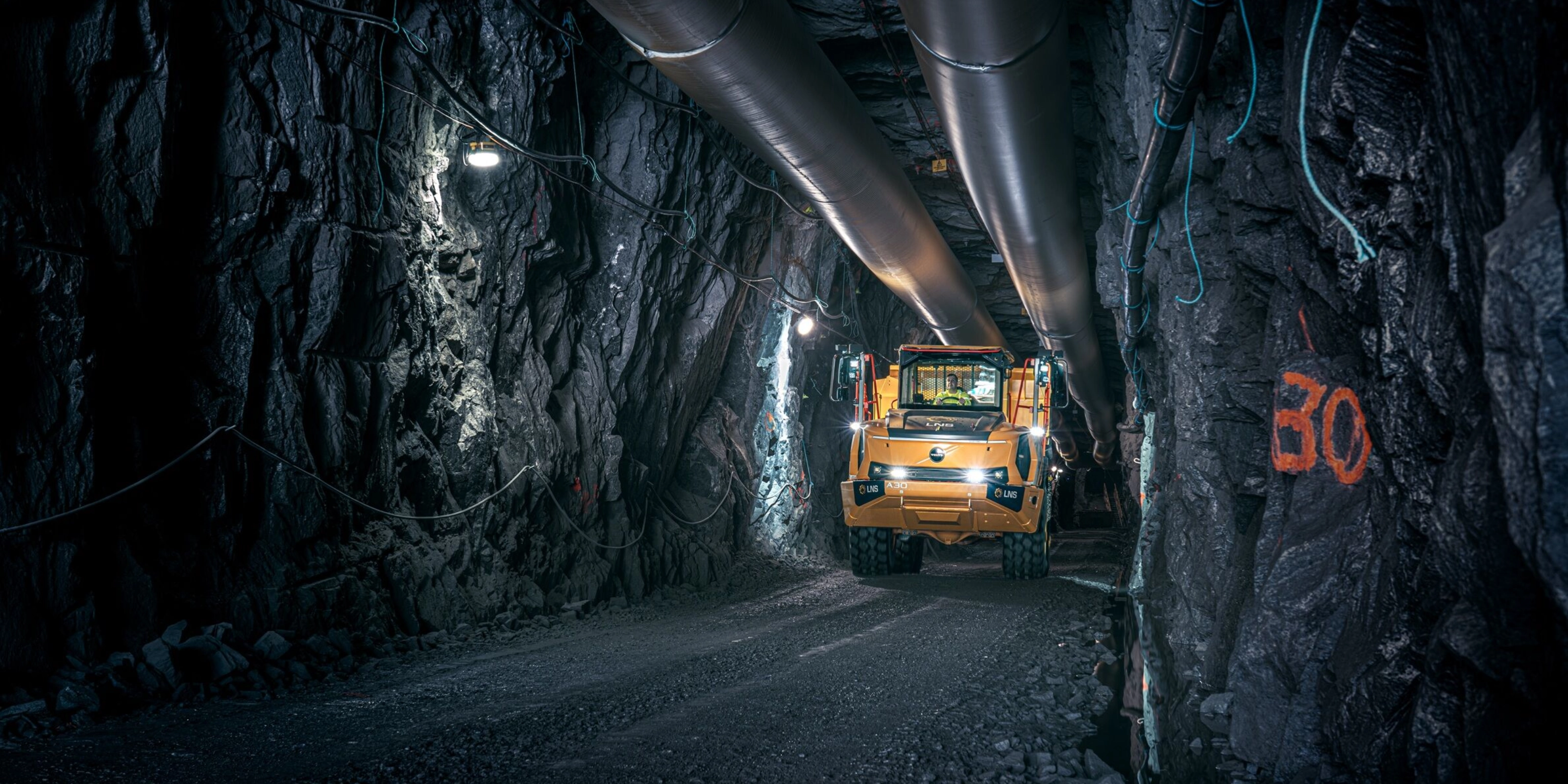 Orange Volvo truck driving through an underground mining tunnel.