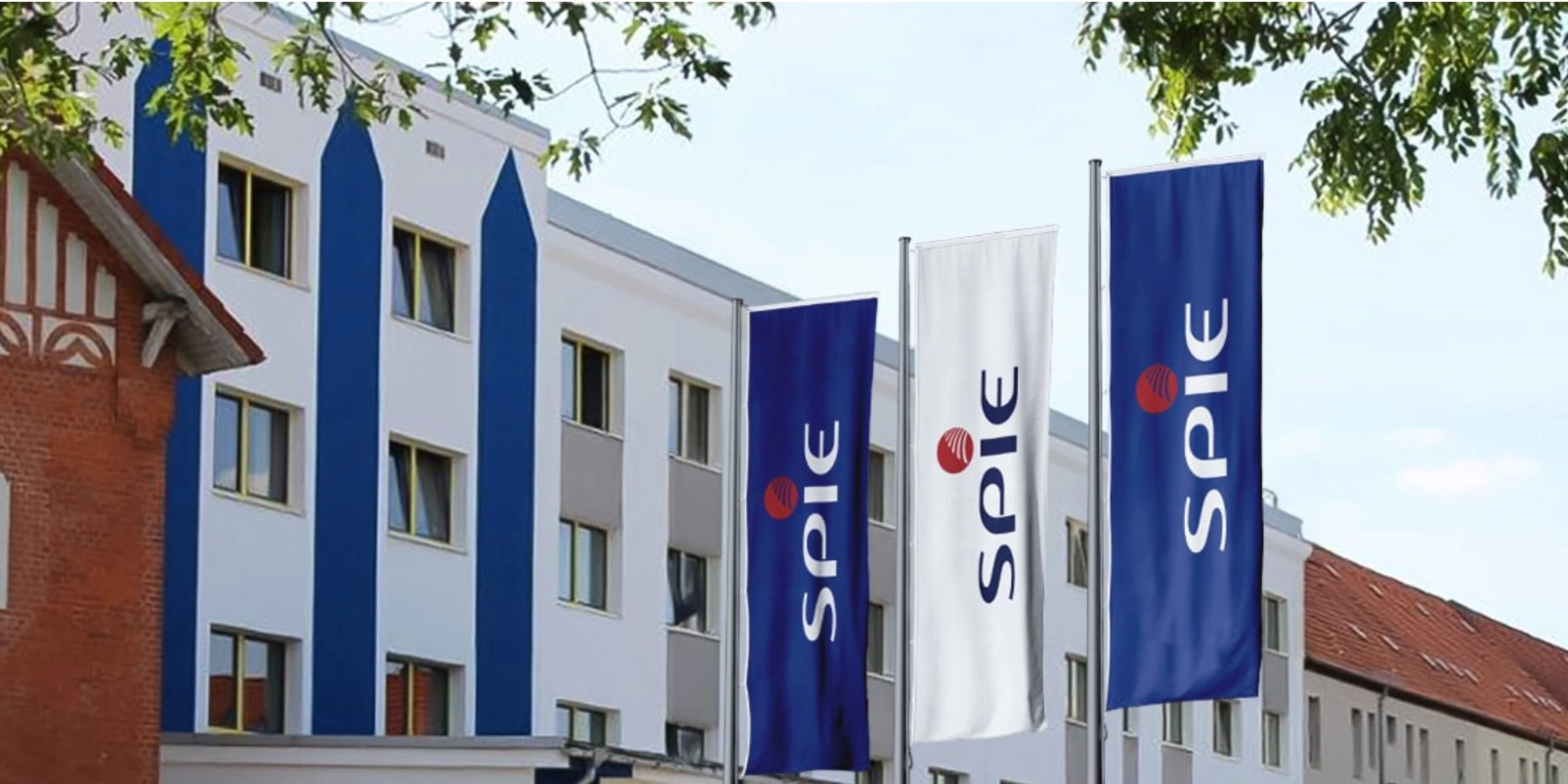 SPIE-Gebäude mit mehreren blauen SPIE-Flaggen an der Fassade.