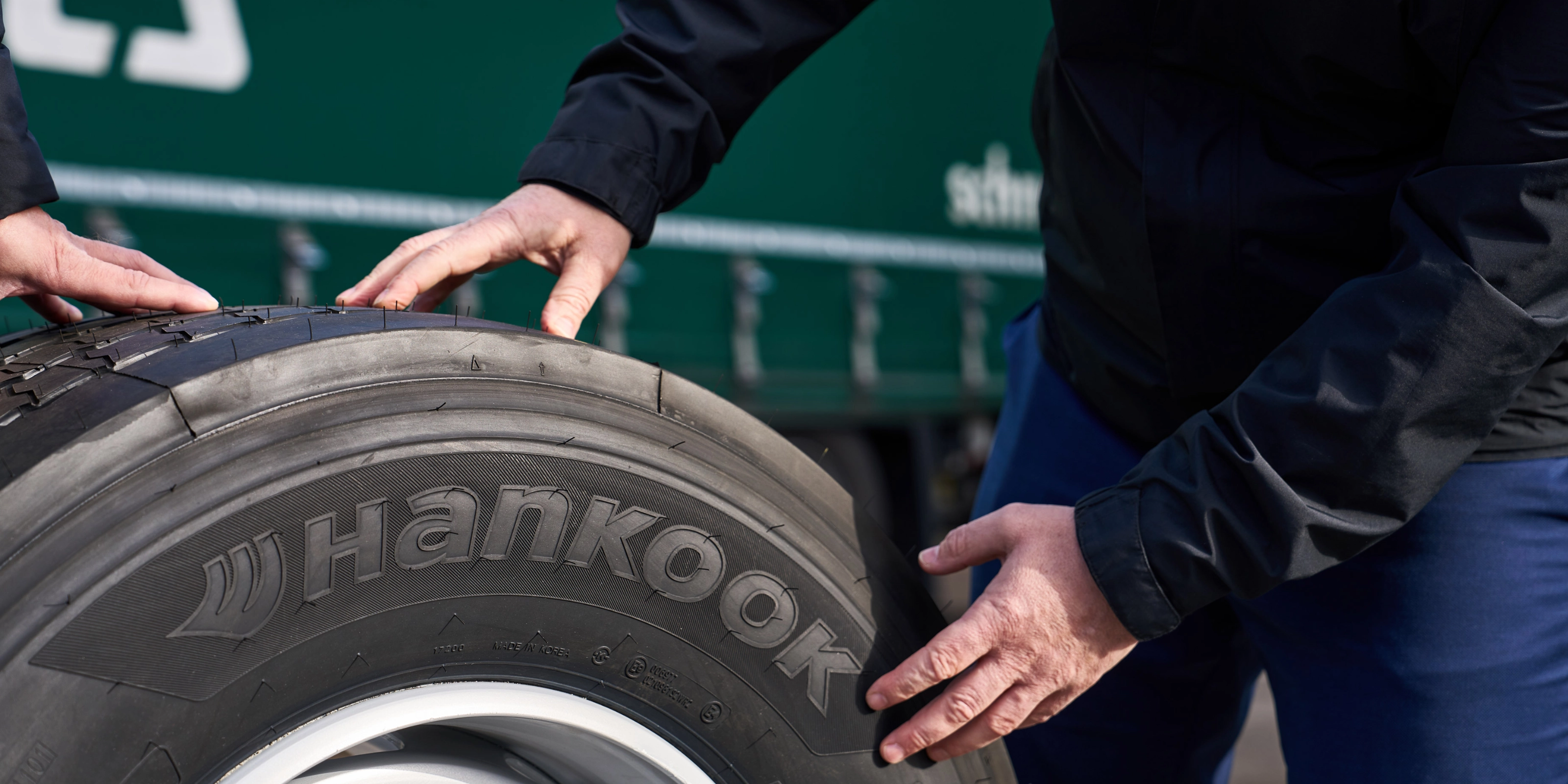 Hände prüfen einen Hankook-Lkw-Reifen auf einer Felge.