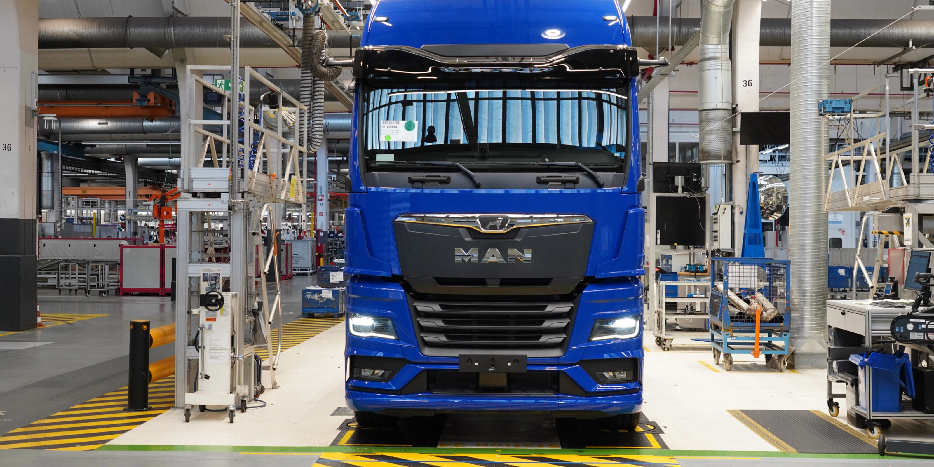 Blauer MAN-Lkw auf einer Produktionslinie in einer modernen Fertigungshalle.