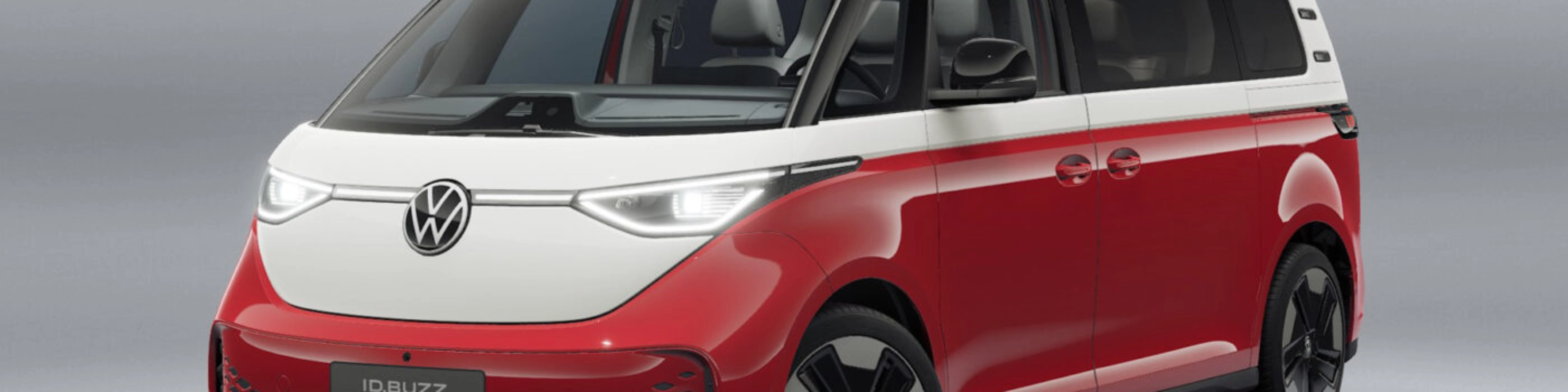 Rot-weißer Volkswagen Van in Frontansicht vor neutralem Studiohintergrund.