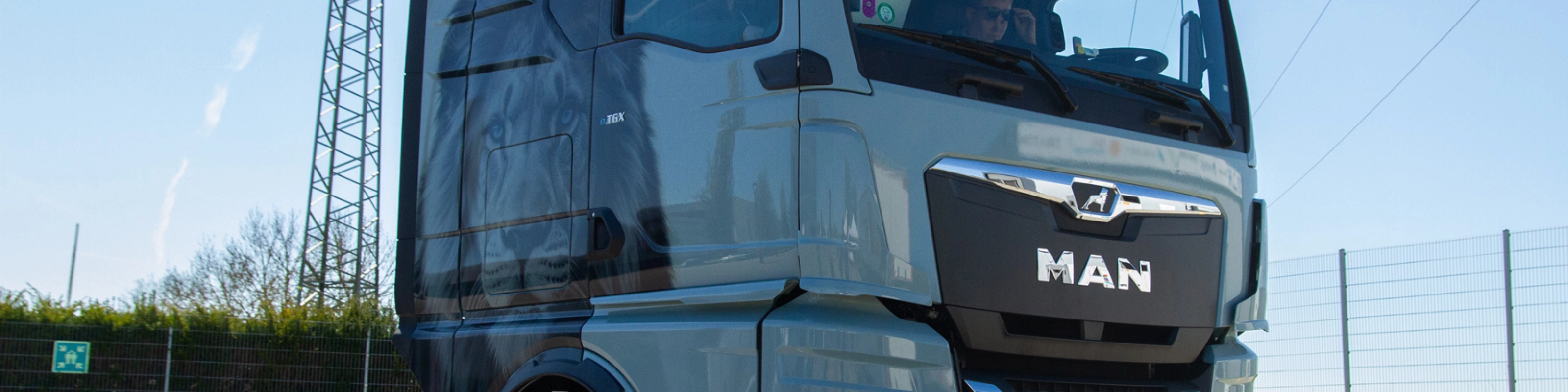 Light blue MAN truck in three-quarter front view on an open road.