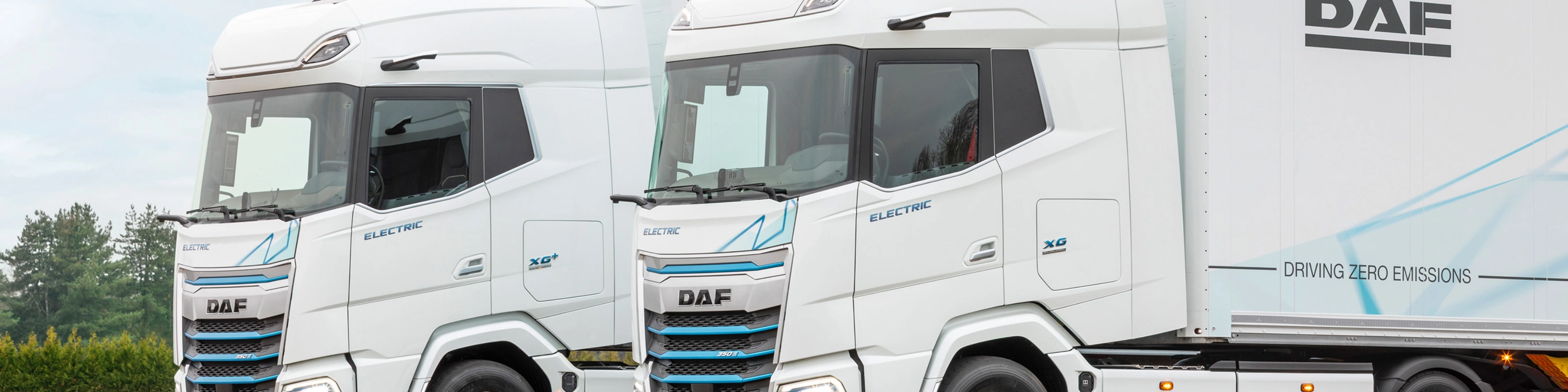 Two DAF electric trucks parked side by side outdoors.