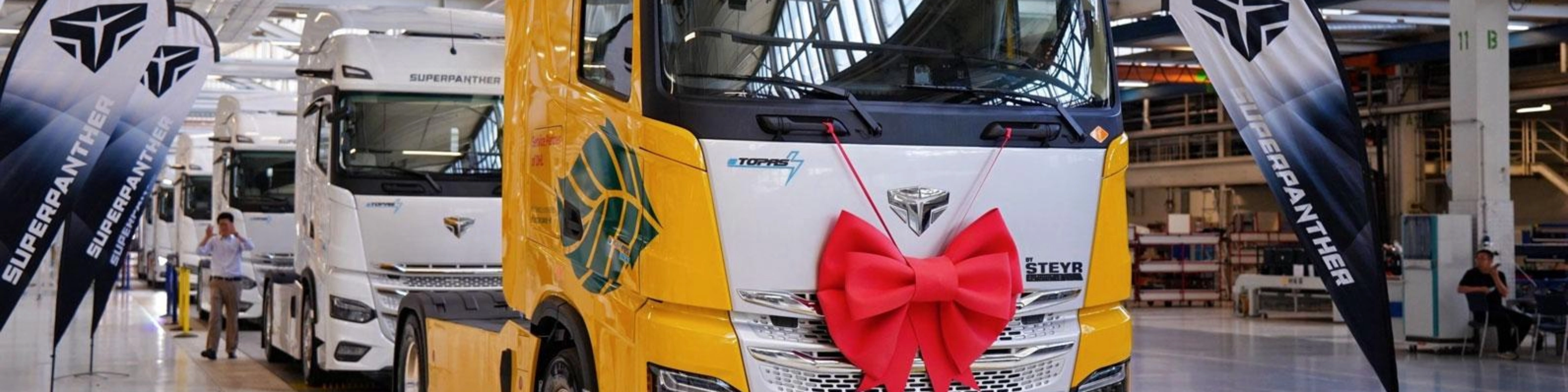 DHL electric truck with a red gift bow displayed inside a production hall.