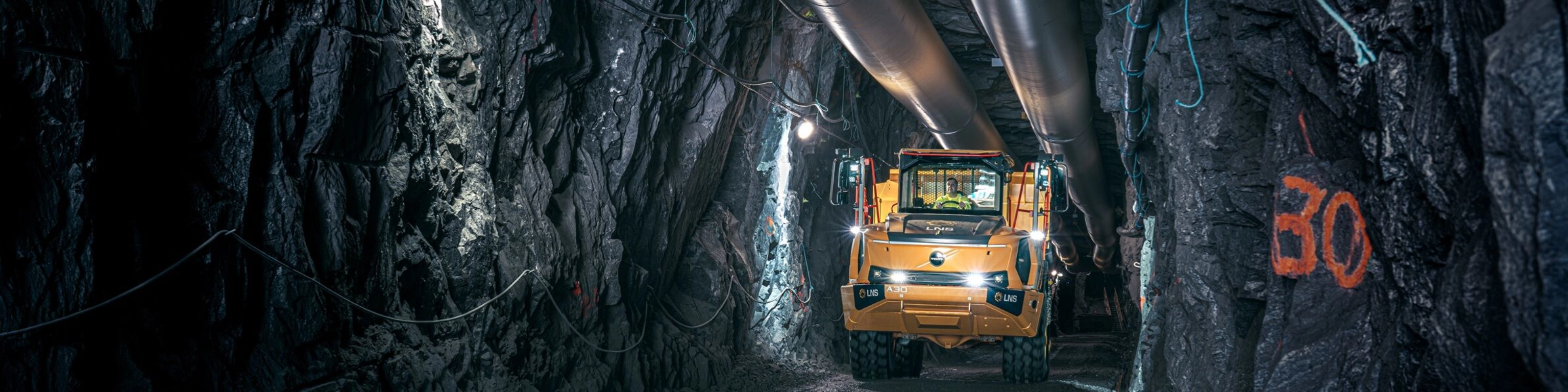 Orange Volvo truck driving through an underground mining tunnel.