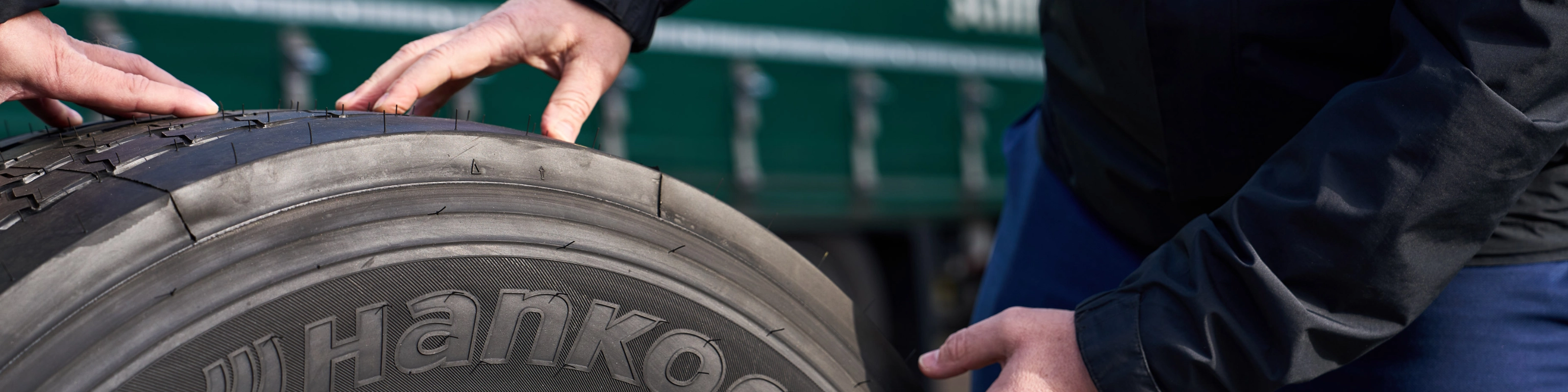 Hände prüfen einen Hankook-Lkw-Reifen auf einer Felge.
