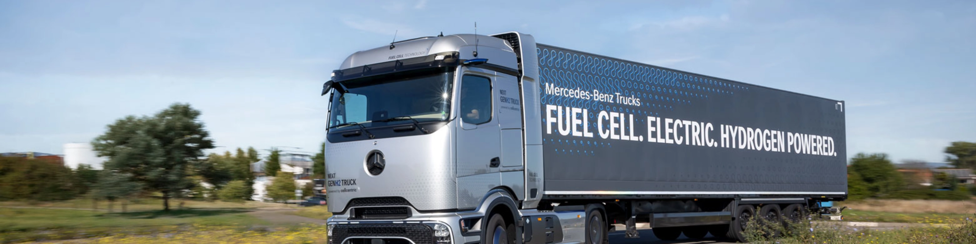Wasserstoffbetriebener Mercedes-Lkw fährt auf einer kurvigen Straße im ländlichen Gebiet.