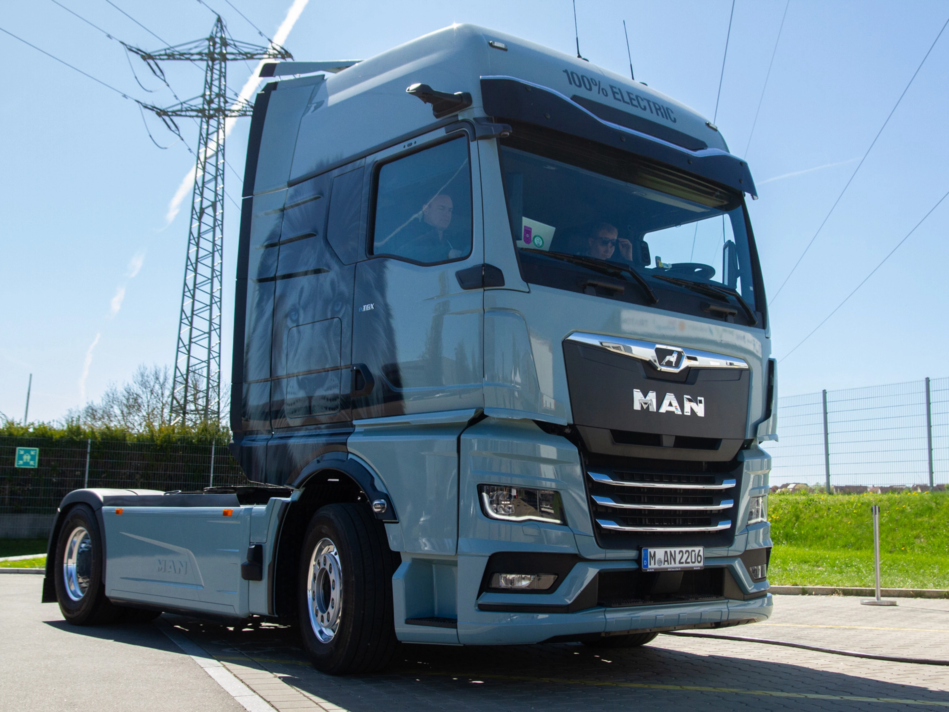 Light blue MAN truck in three-quarter front view on an open road.