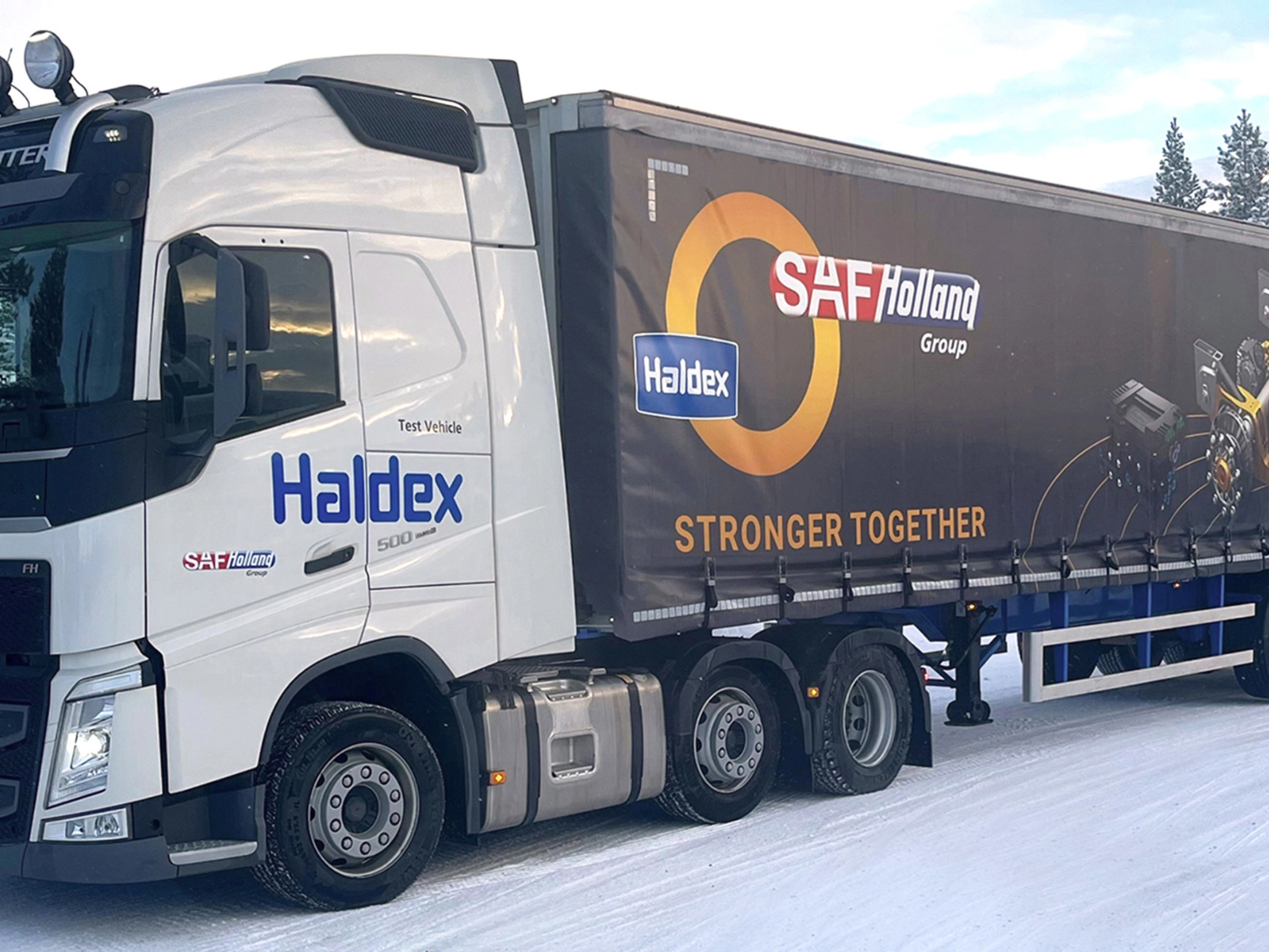 SAF-Holland truck with trailer driving on a snow-covered road.