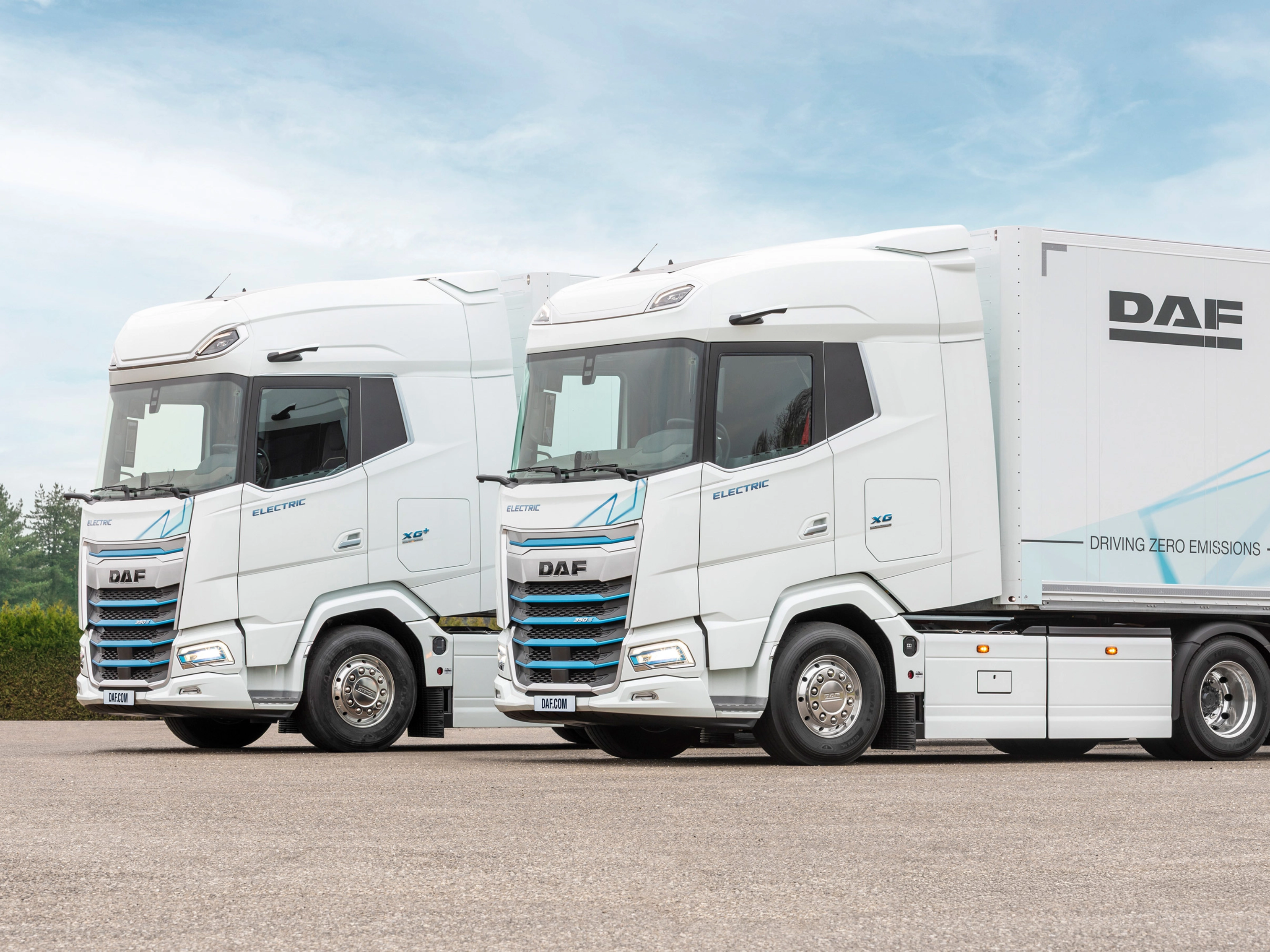 Two DAF electric trucks parked side by side outdoors.