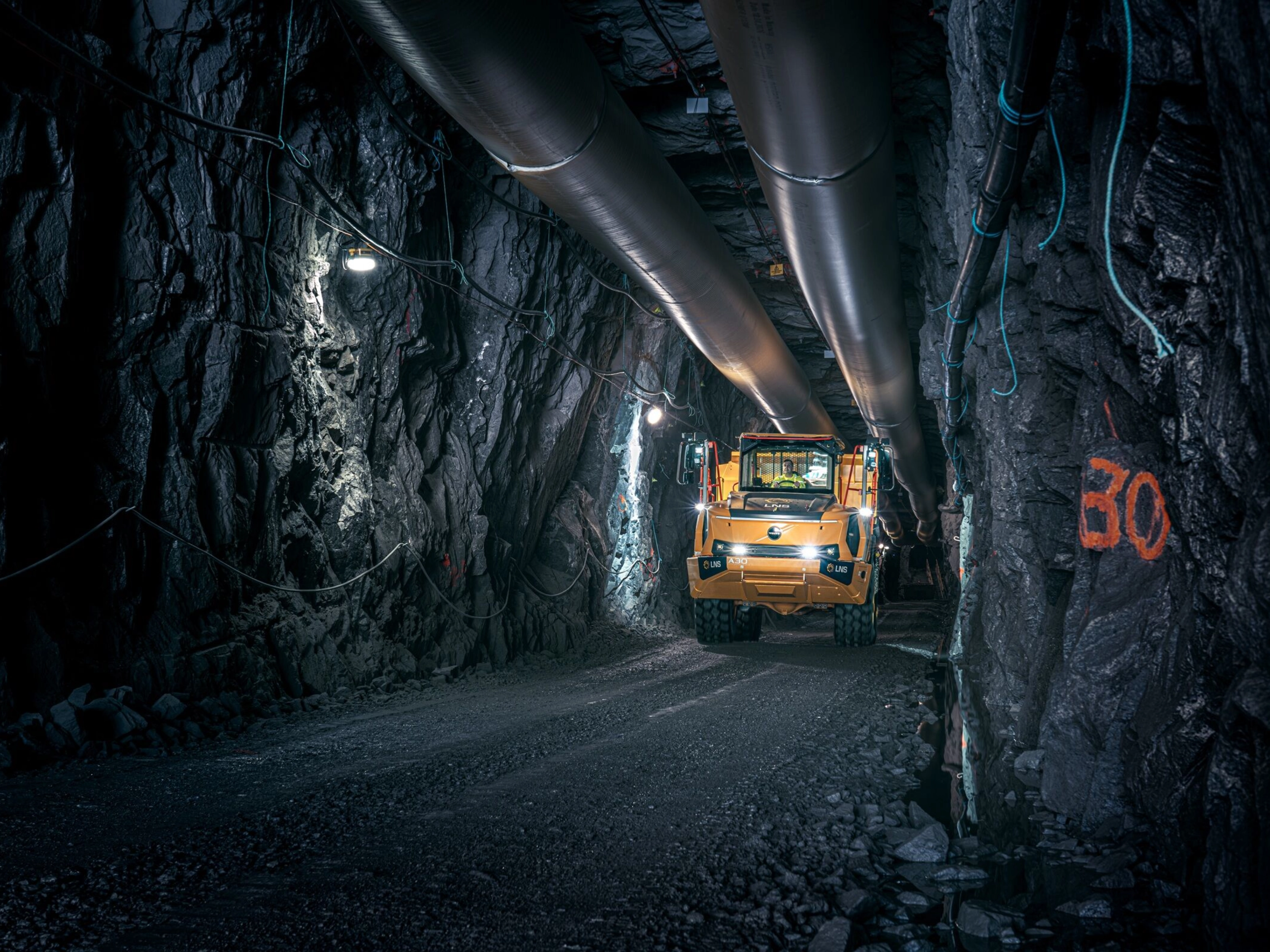 Orange Volvo truck driving through an underground mining tunnel.