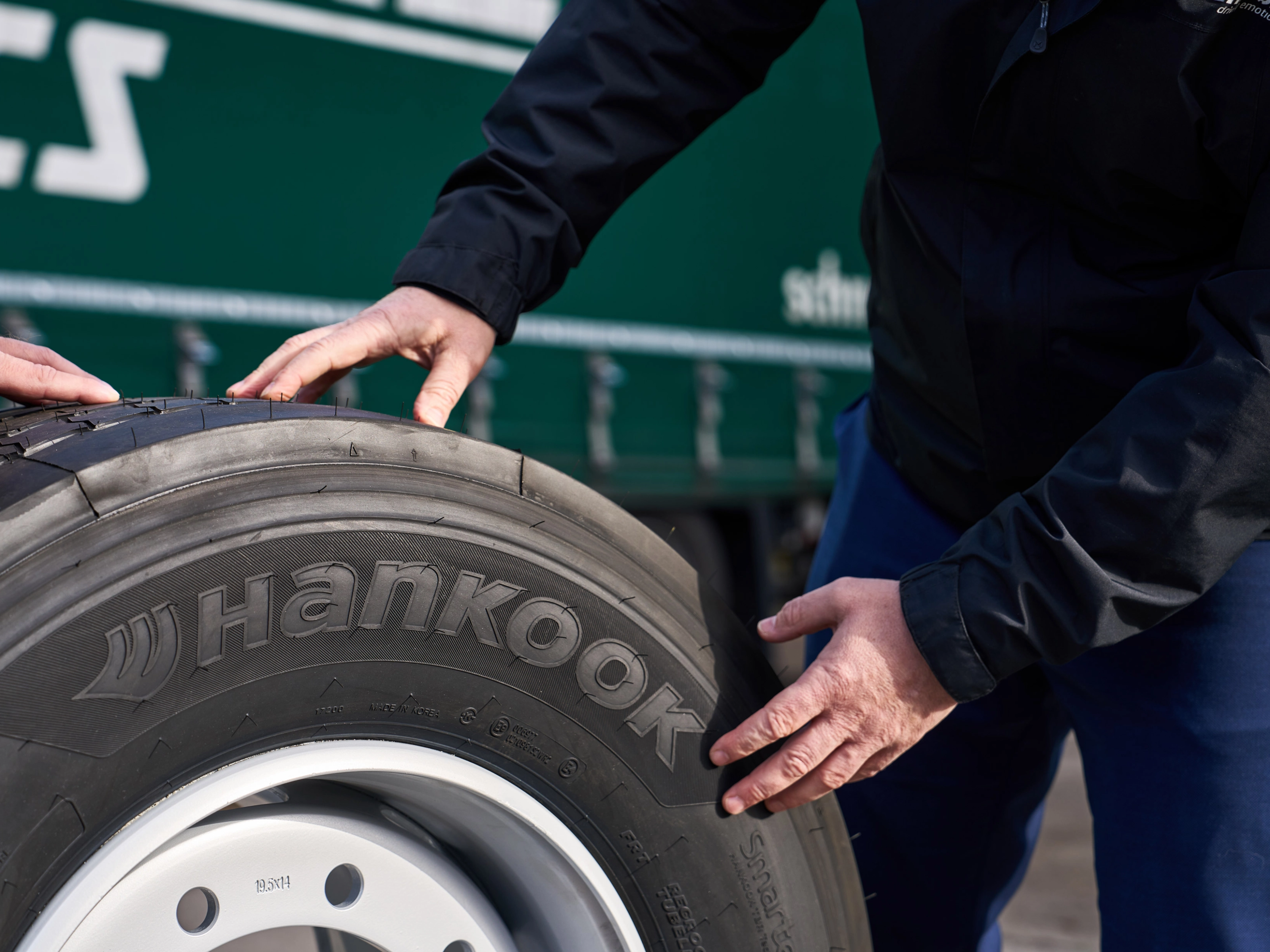 Hände prüfen einen Hankook-Lkw-Reifen auf einer Felge.