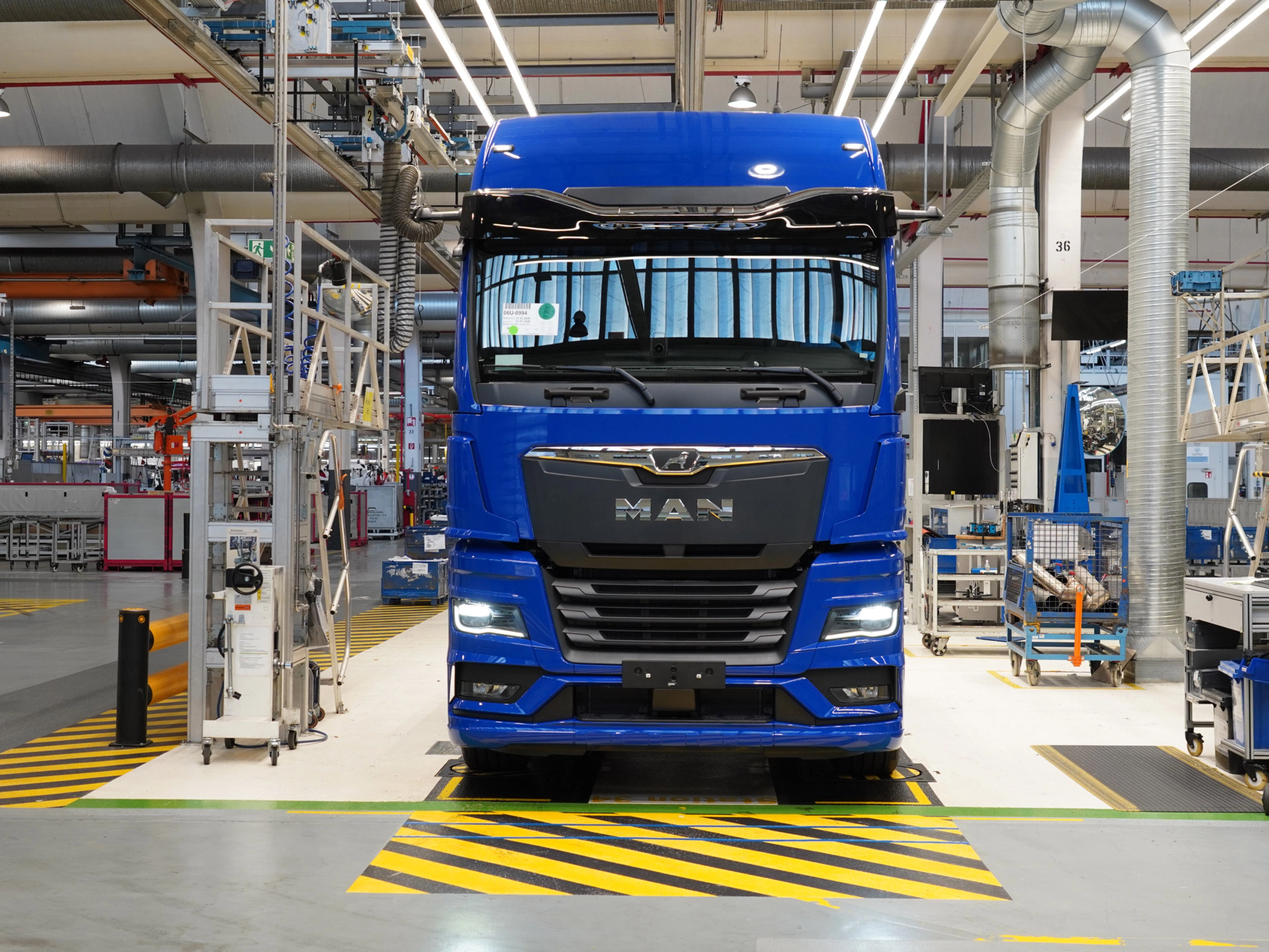 Blauer MAN-Lkw auf einer Produktionslinie in einer modernen Fertigungshalle.