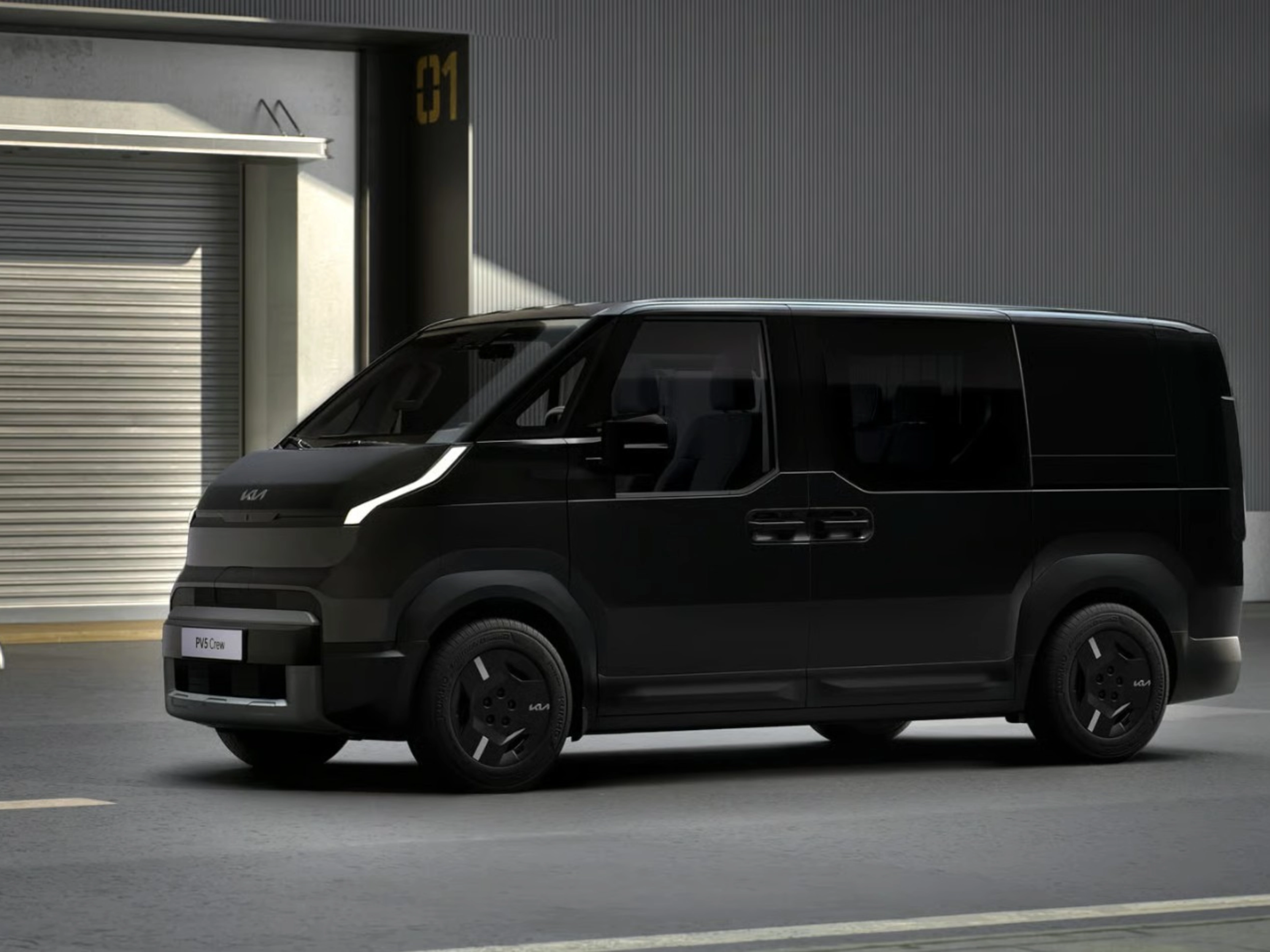 Schwarzer Kia-Van steht vor Industriegebäuden mit geschlossenen Rolltoren.