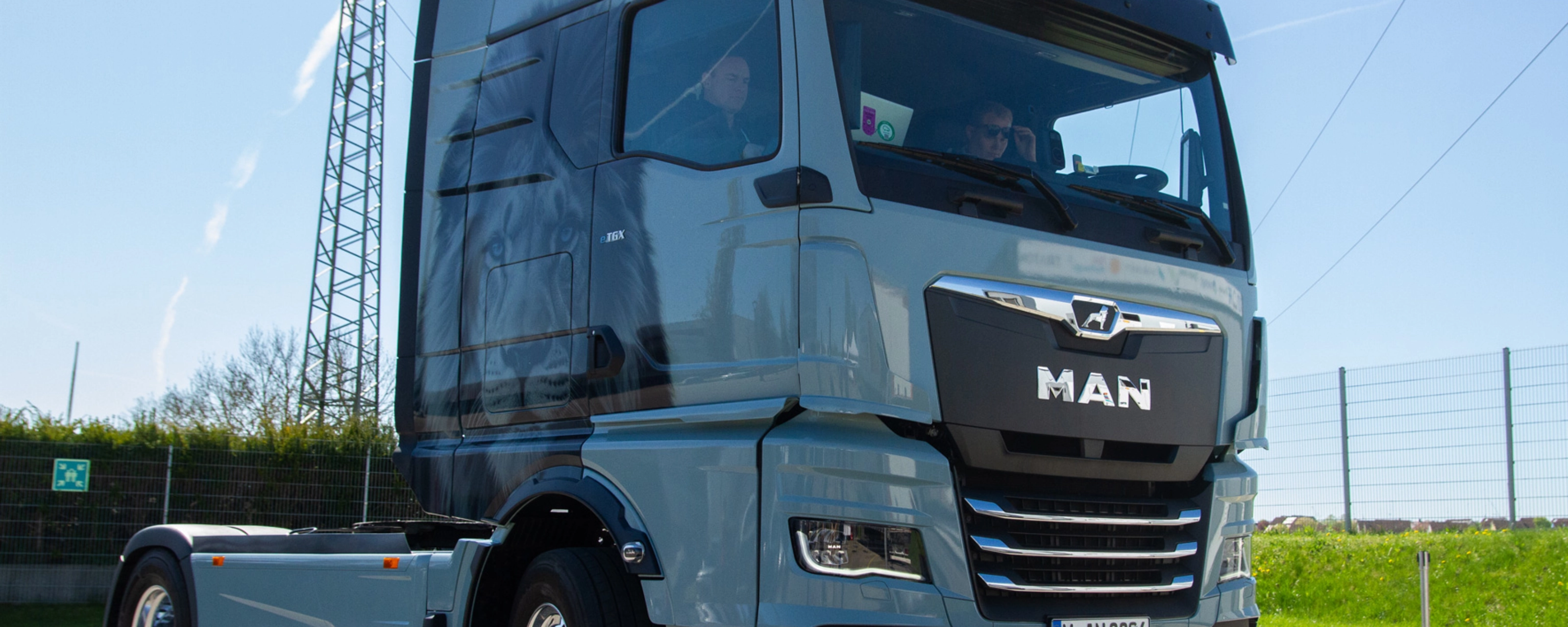 Light blue MAN truck in three-quarter front view on an open road.