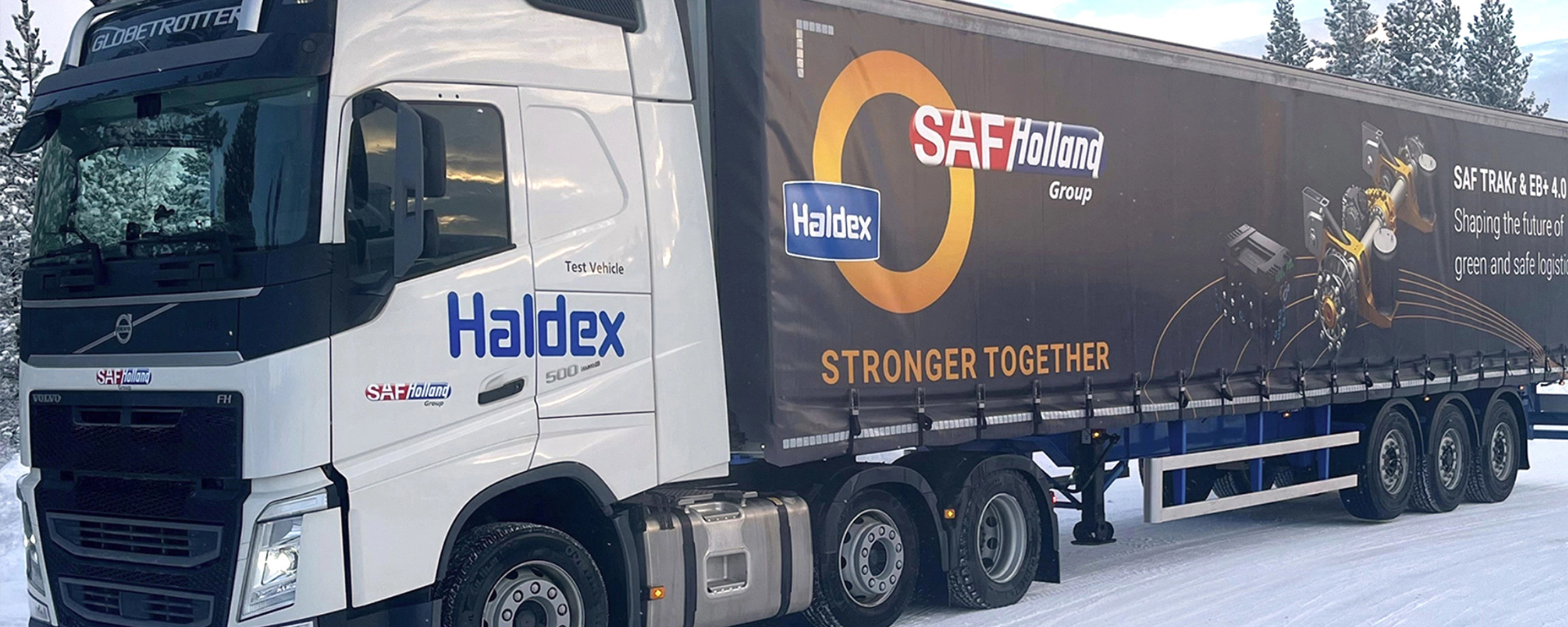 SAF-Holland truck with trailer driving on a snow-covered road.