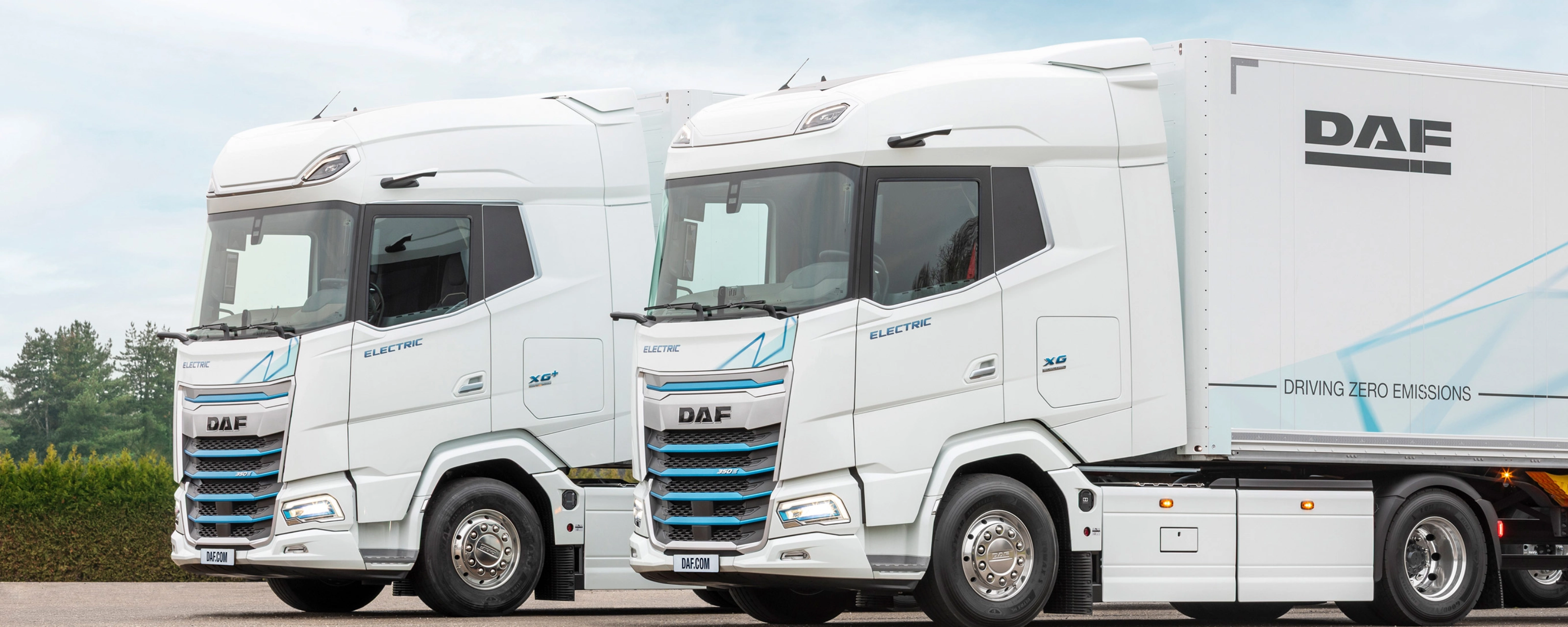 Two DAF electric trucks parked side by side outdoors.