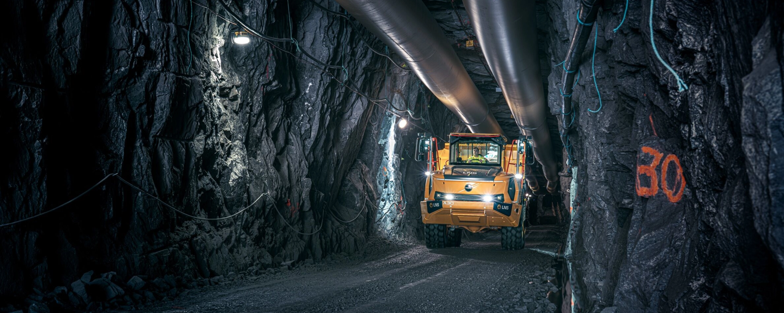 Orange Volvo truck driving through an underground mining tunnel.