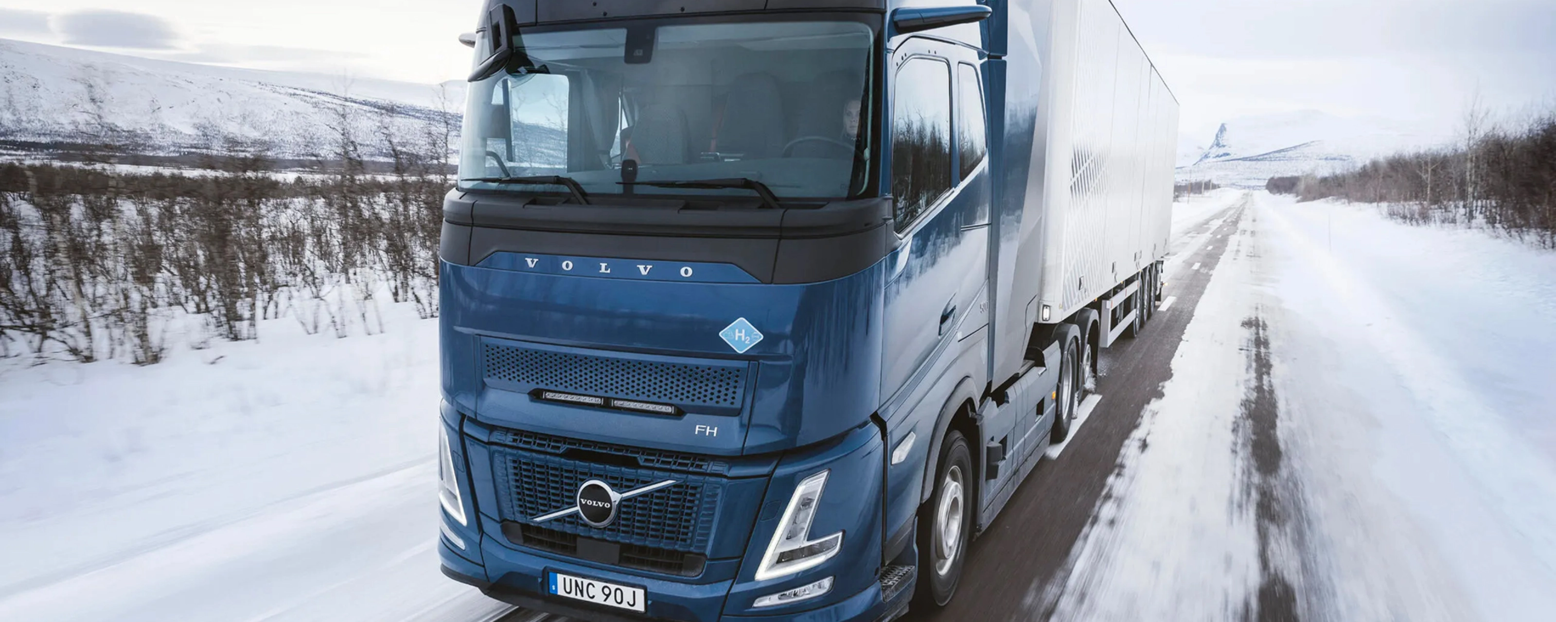 Wasserstoffbetriebener Volvo-Lkw fährt auf verschneiter Straße durch Winterlandschaft.