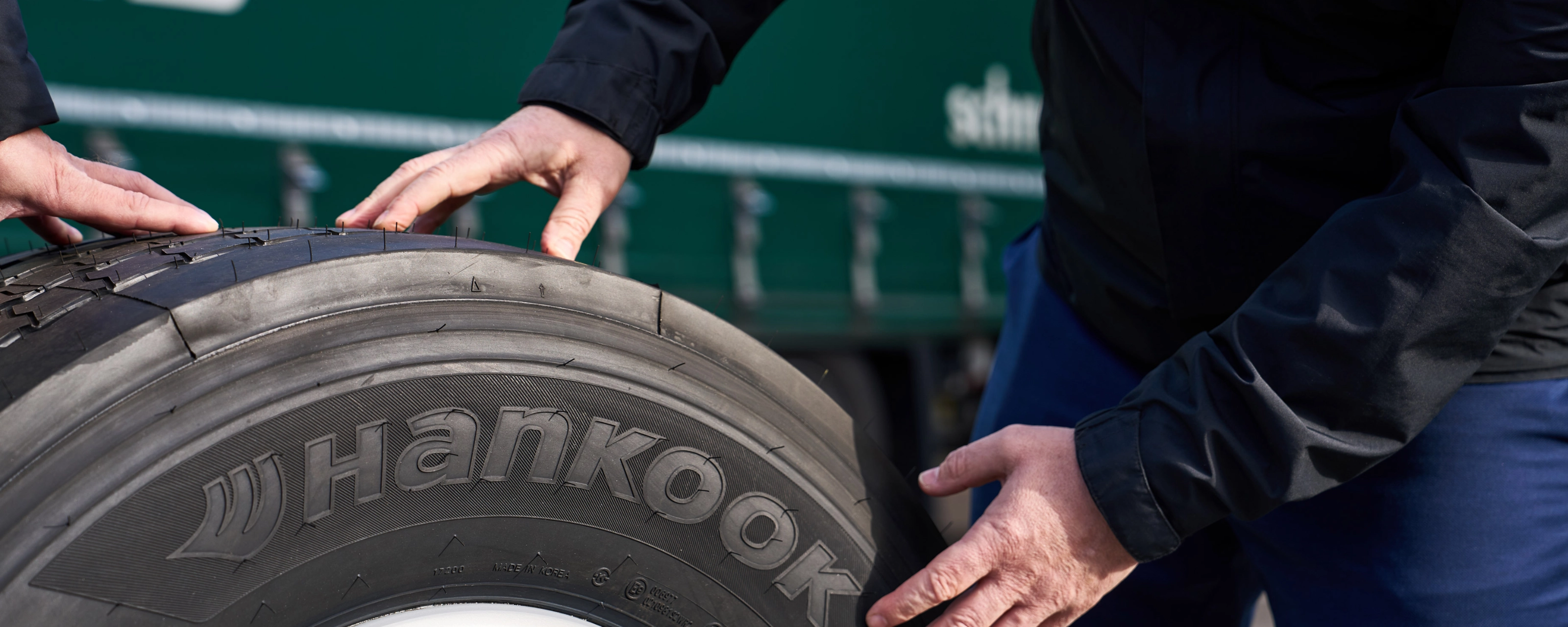 Hände prüfen einen Hankook-Lkw-Reifen auf einer Felge.