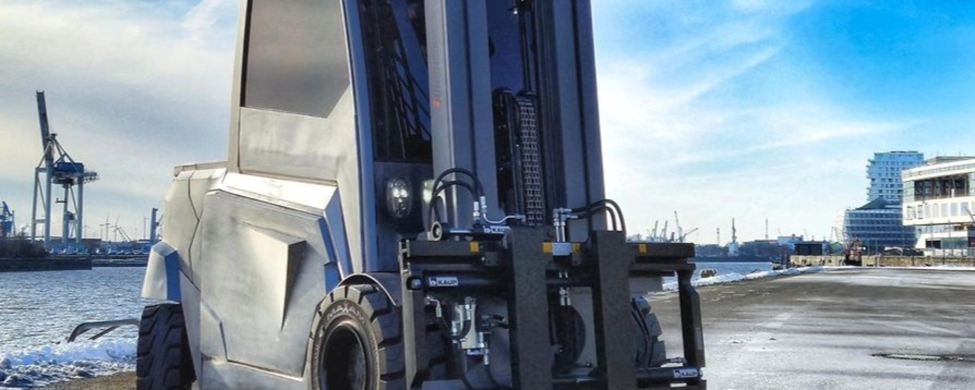 Large industrial forklift parked at a harbor loading area.