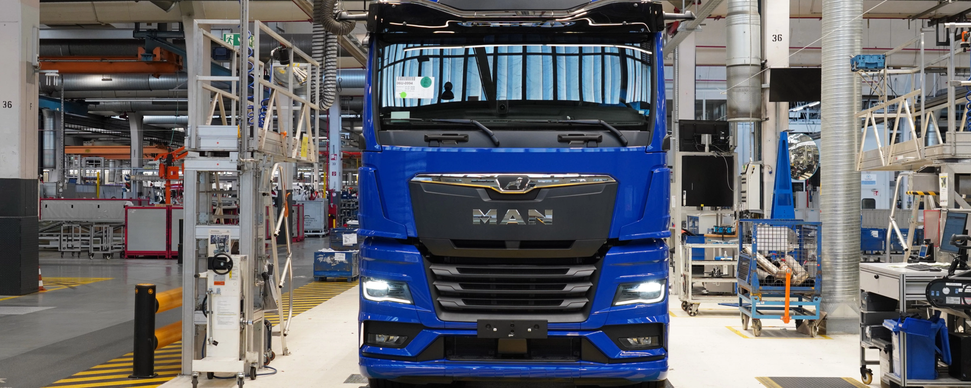 Blauer MAN-Lkw auf einer Produktionslinie in einer modernen Fertigungshalle.
