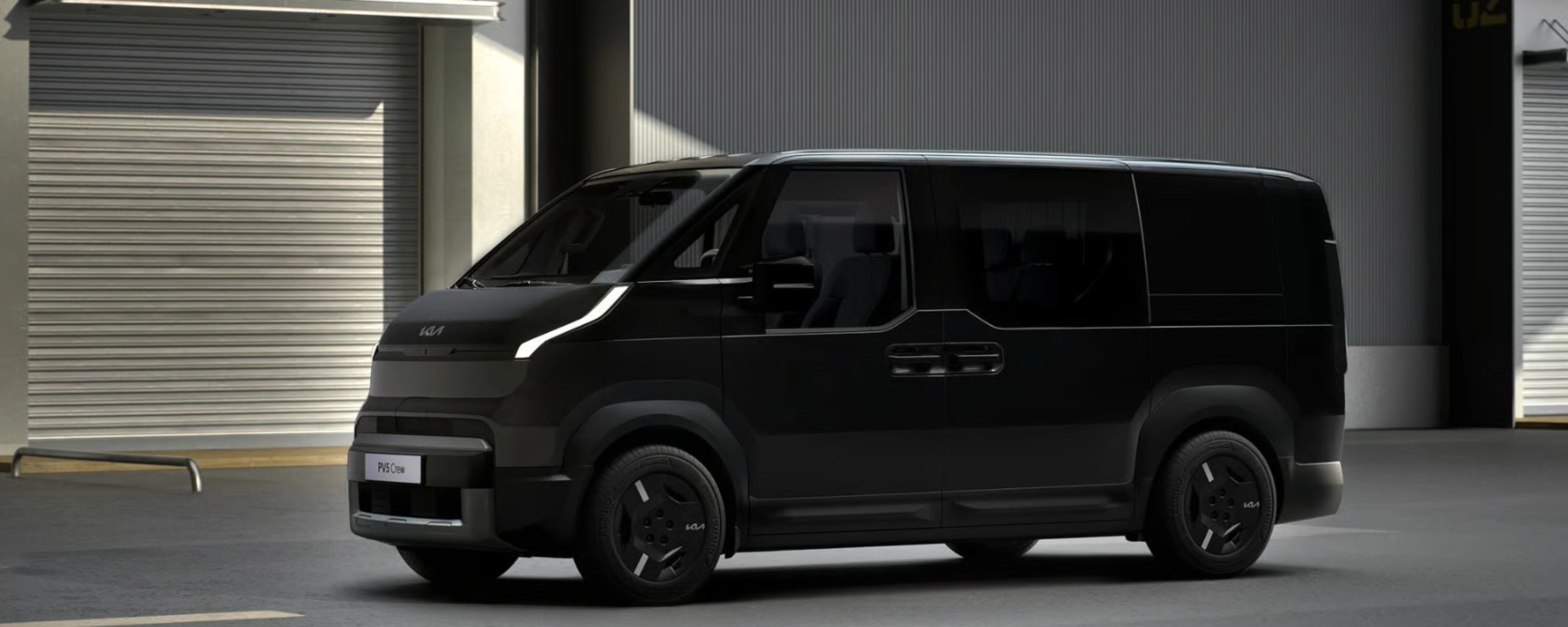 Schwarzer Kia-Van steht vor Industriegebäuden mit geschlossenen Rolltoren.