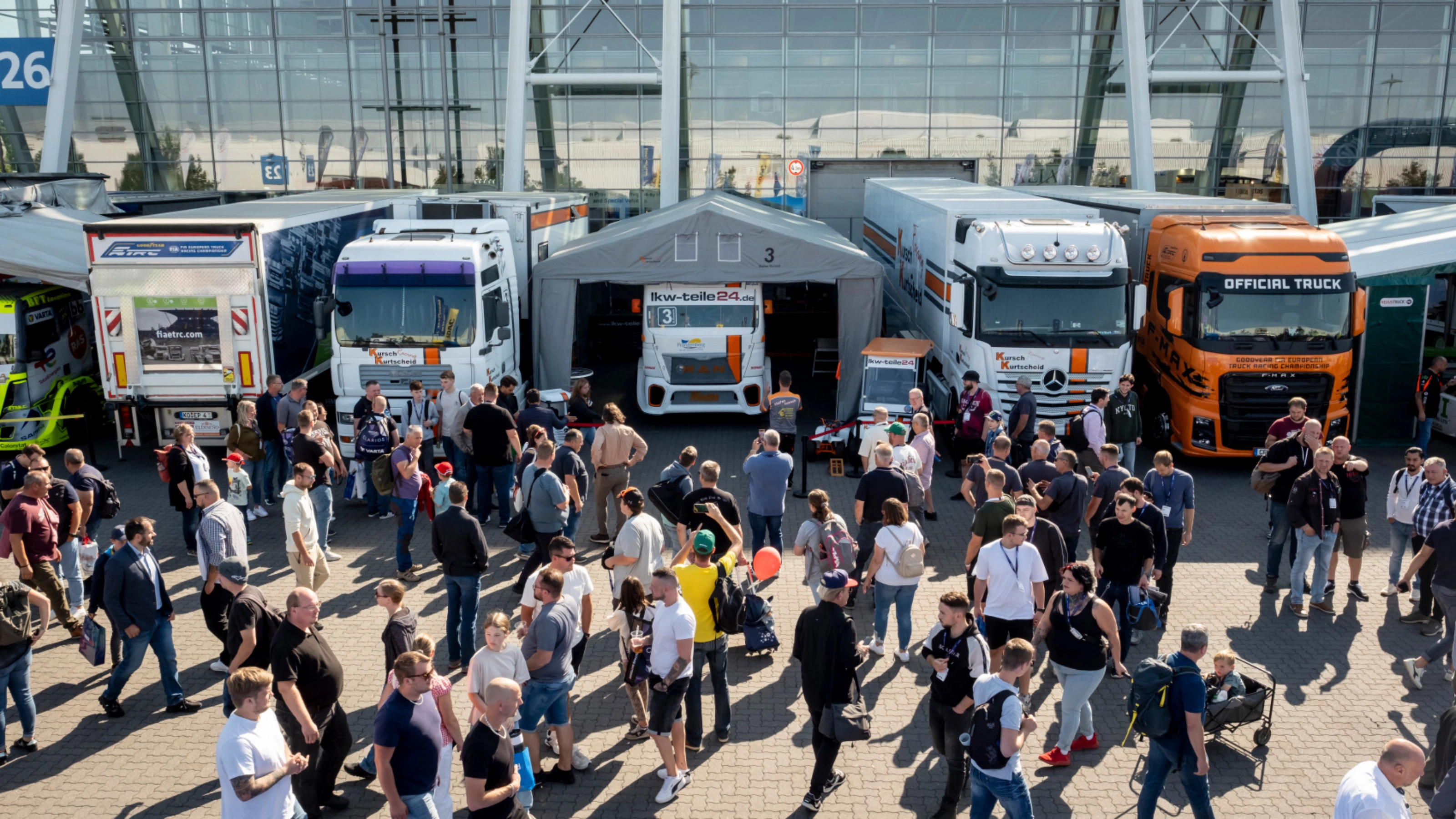 Besucher erkunden eine Lkw-Ausstellung mit Fahrzeugen und Messeständen.