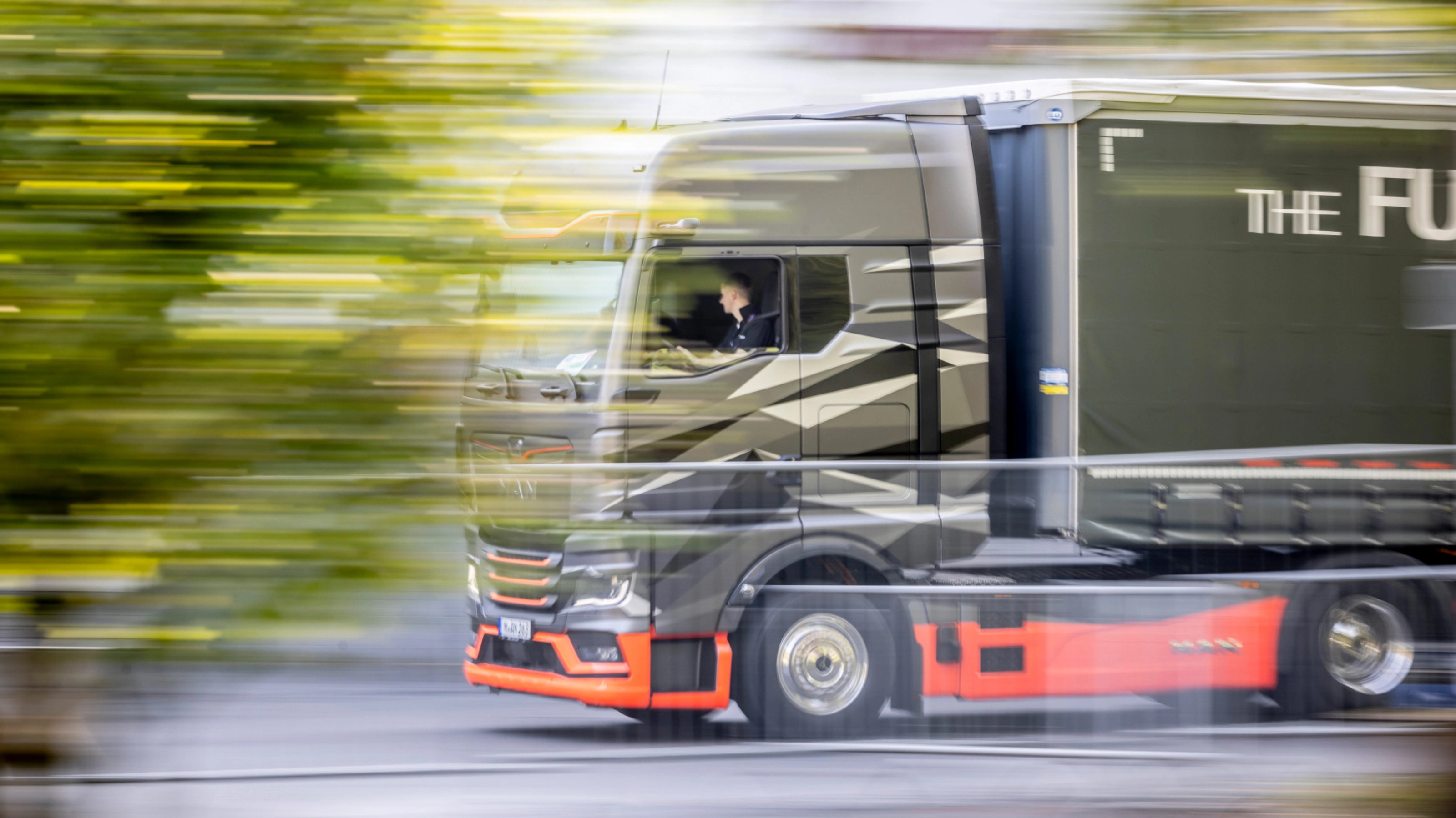 Moderner Lkw fährt auf einer Straße, aufgenommen mit Bewegungsunschärfe.