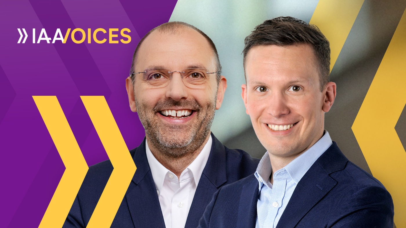 Porträt von Sebastian Tschödrich und Peter Fintl lächelnd vor IAA-Voices-Hintergrund.
