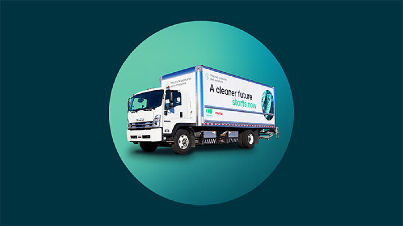 Weißer elektrischer Isuzu-Lkw mit dem Slogan „A cleaner future starts now“ auf der Seite, dargestellt vor einem türkisfarbenen Hintergrund.