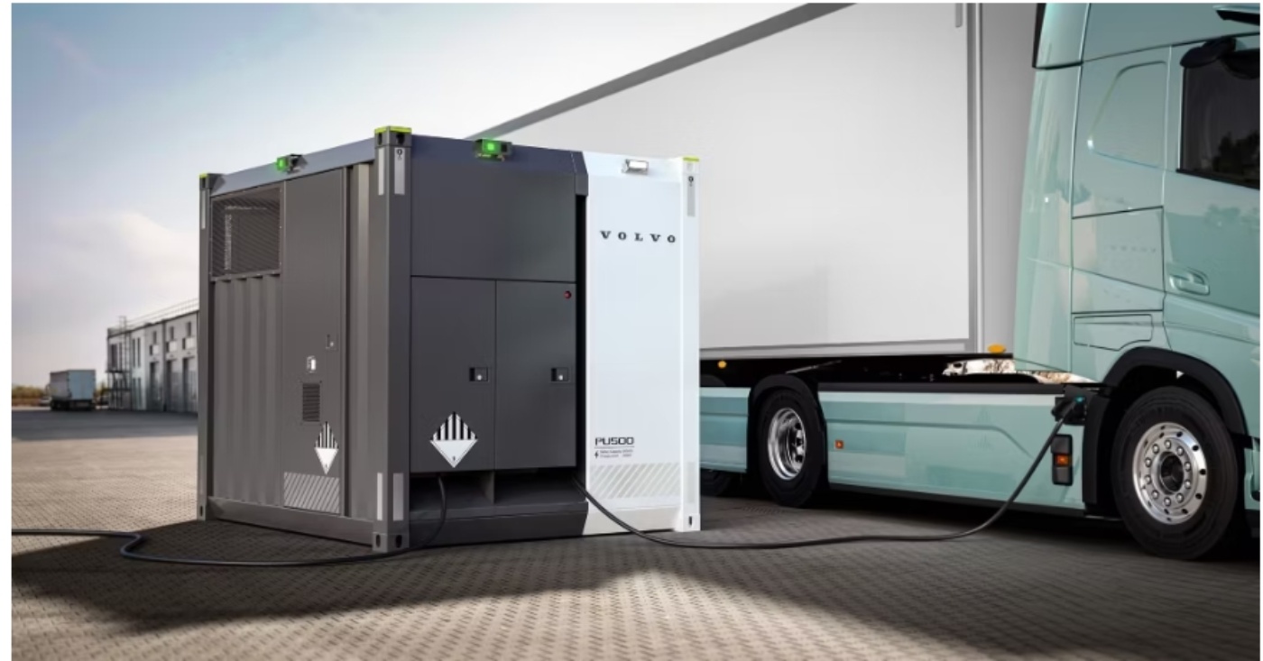 Elektrischer Volvo-Lkw ist an eine mobile Ladestation mit der Bezeichnung „PU500“ auf einem Industriegelände angeschlossen.
