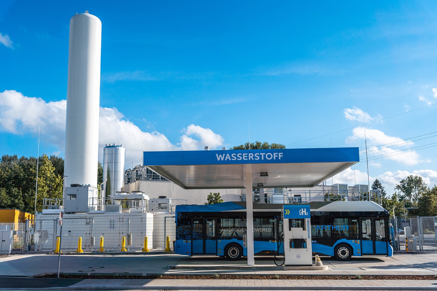 Blue hydrogen bus refueling at a hydrogen station labeled "Wasserstoff".