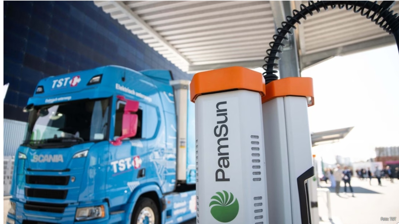 Elektro-Lkw an Ladestation mit PamSun-Logo im Vordergrund.