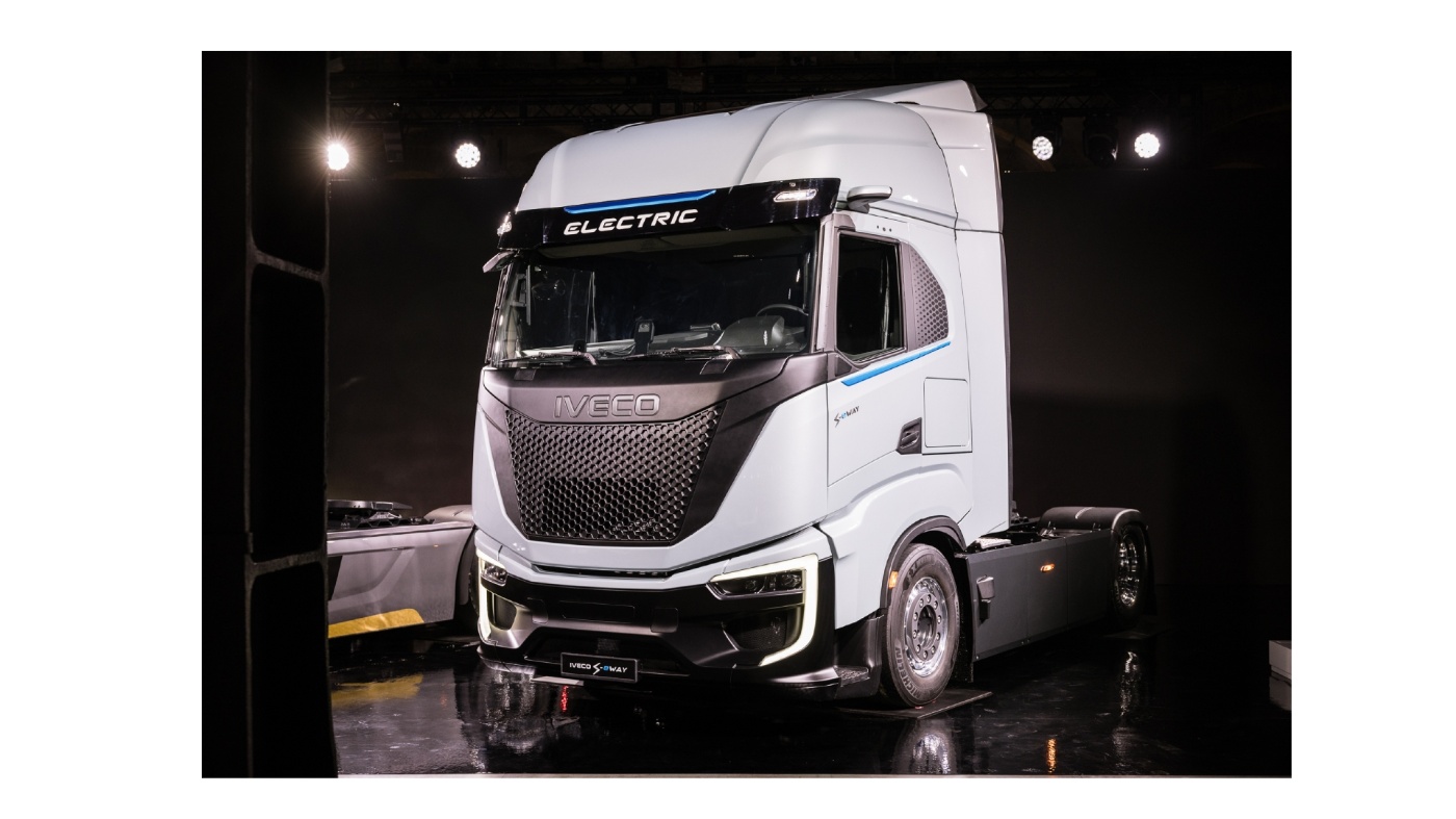 Elektrischer Iveco-Lkw steht ausgeleuchtet auf dunkler Bühne mit glänzendem Boden.