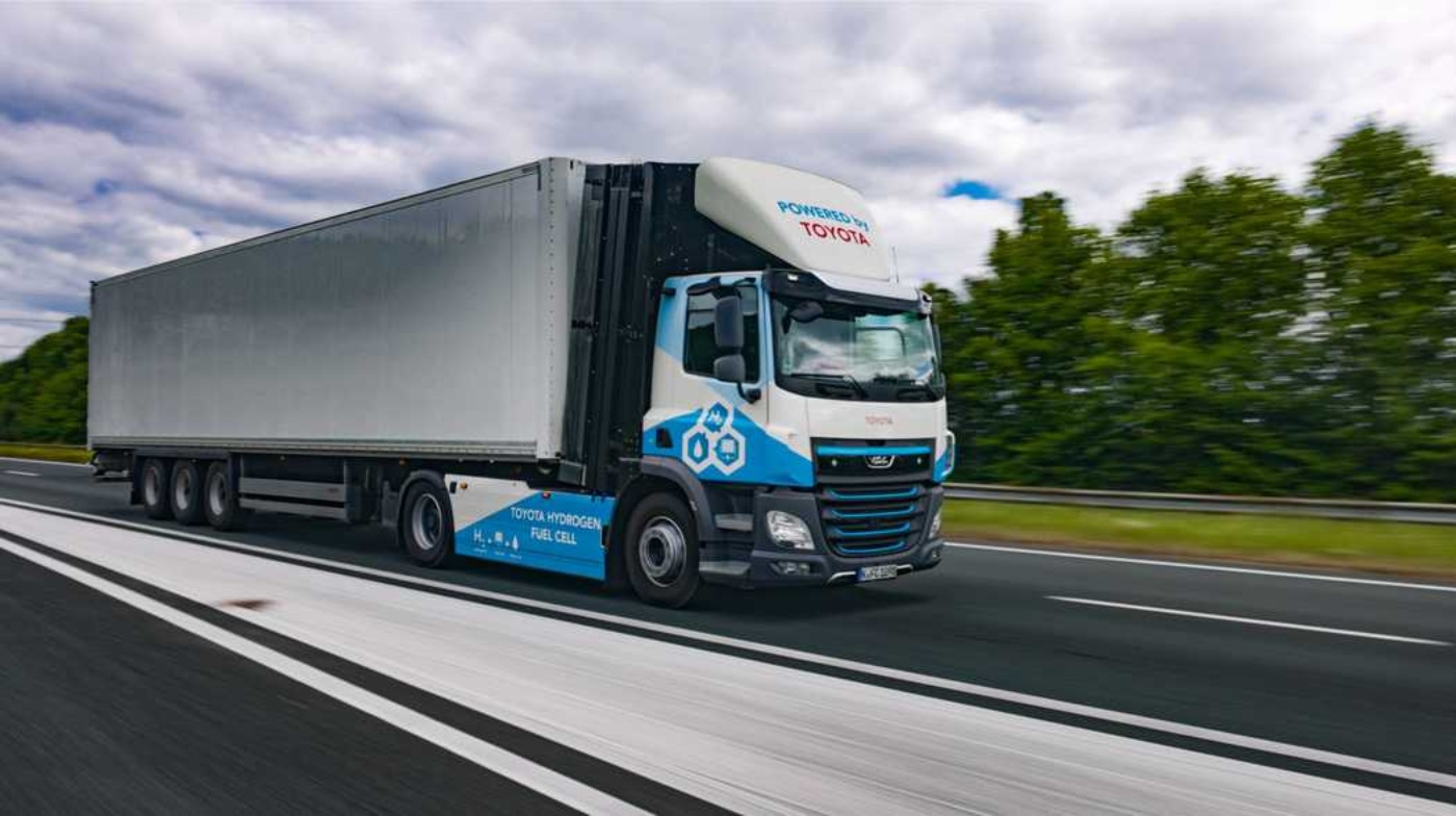 Wasserstoffbetriebener Toyota-Lkw fährt auf der Autobahn an Bäumen vorbei.