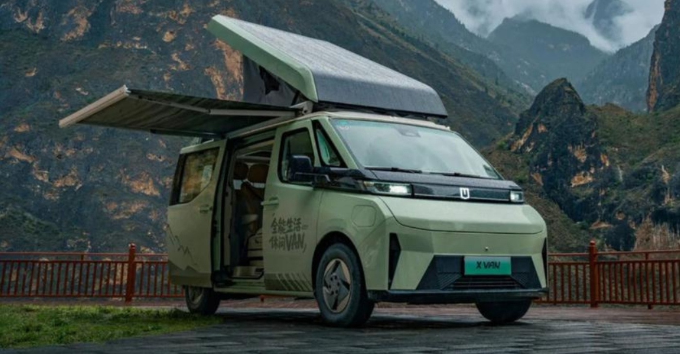 Moderner Campervan mit geöffnetem Dach und Seitentür in einer Berglandschaft geparkt.