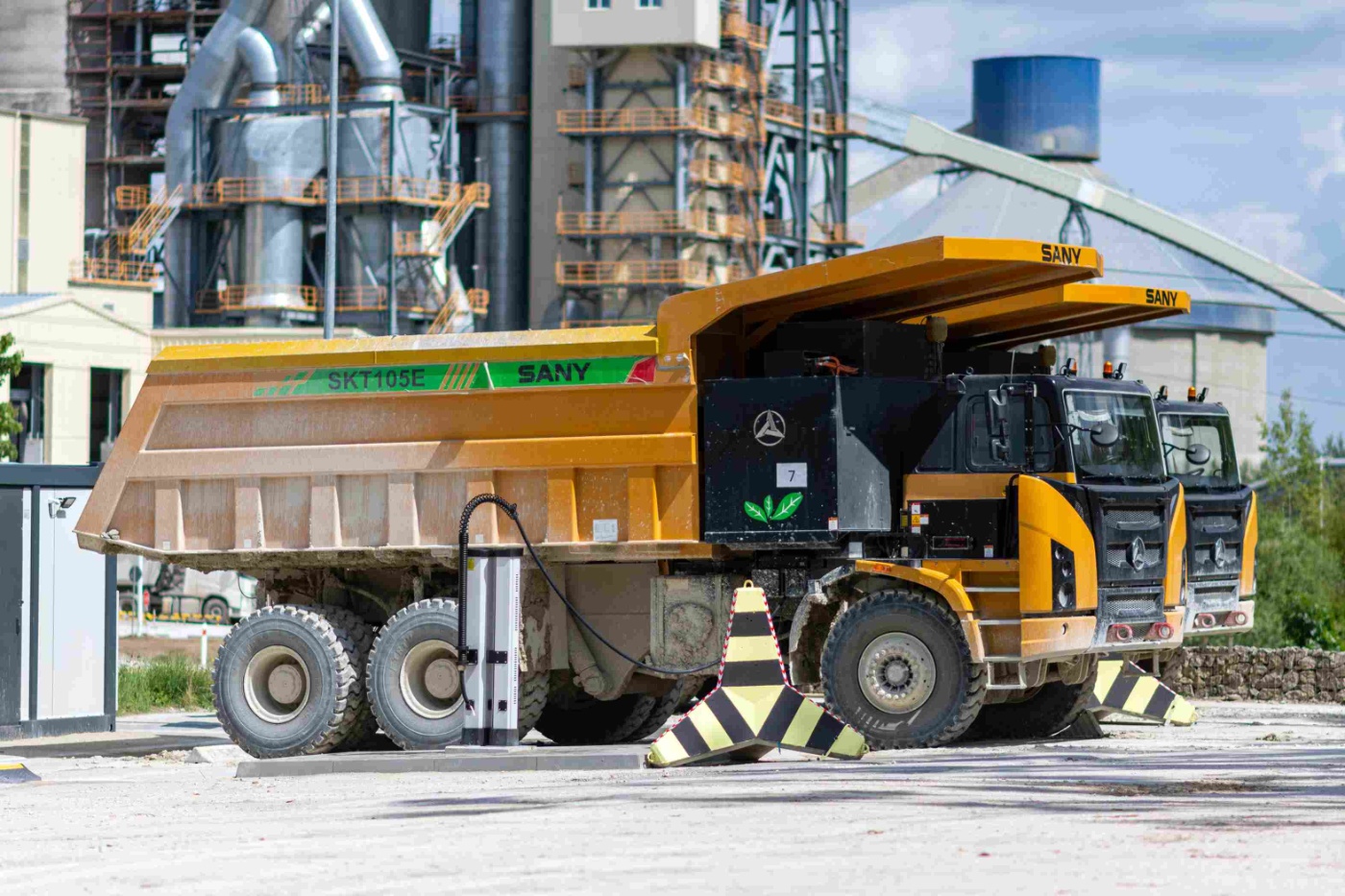 Electric mining trucks are charging at a station in an industrial facility.