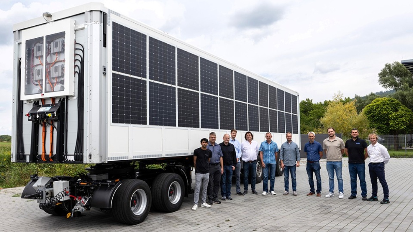 Group stands in front of a truck trailer with integrated solar panels on the side and rear.