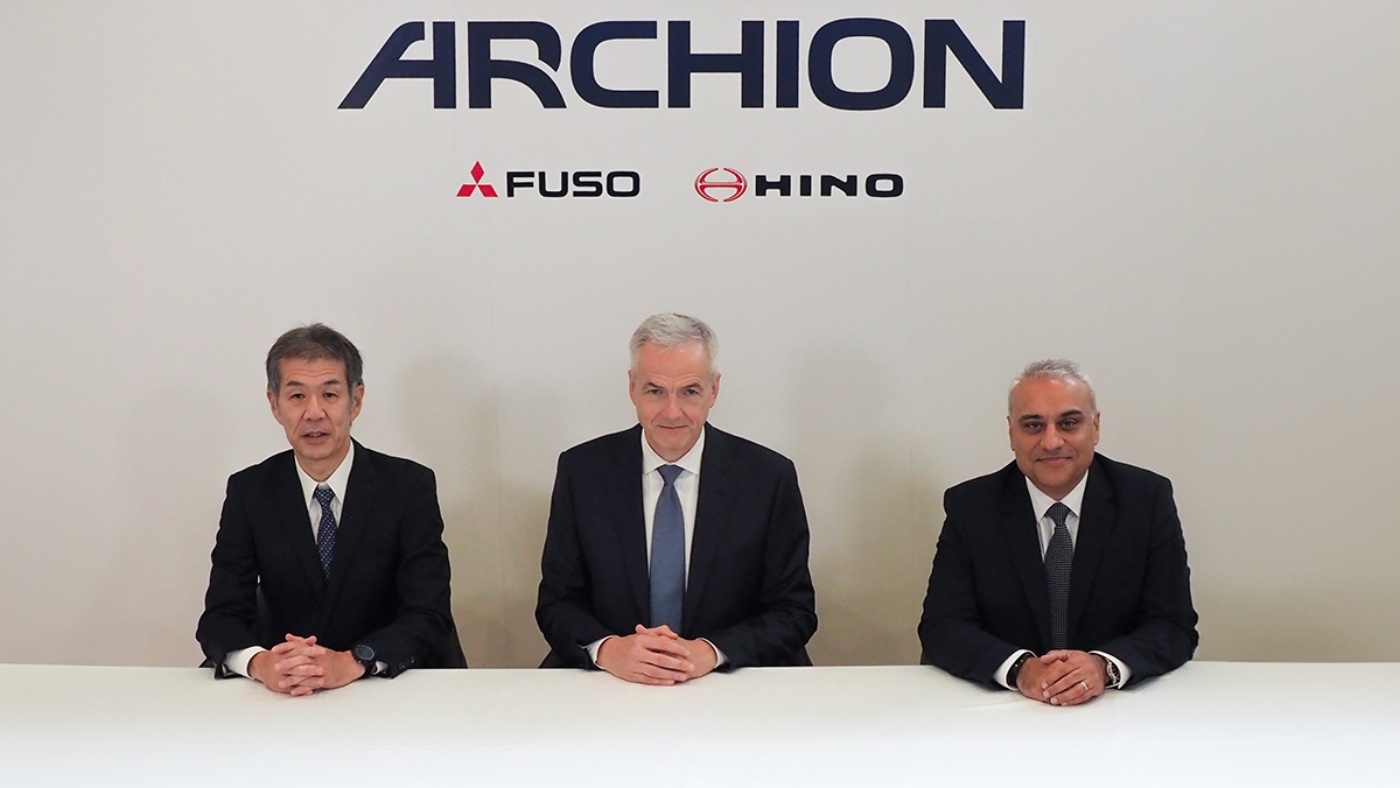 Drei Männer im Anzug sitzen vor dem ARCHION-Logo mit den Logos von Fuso und Hino.