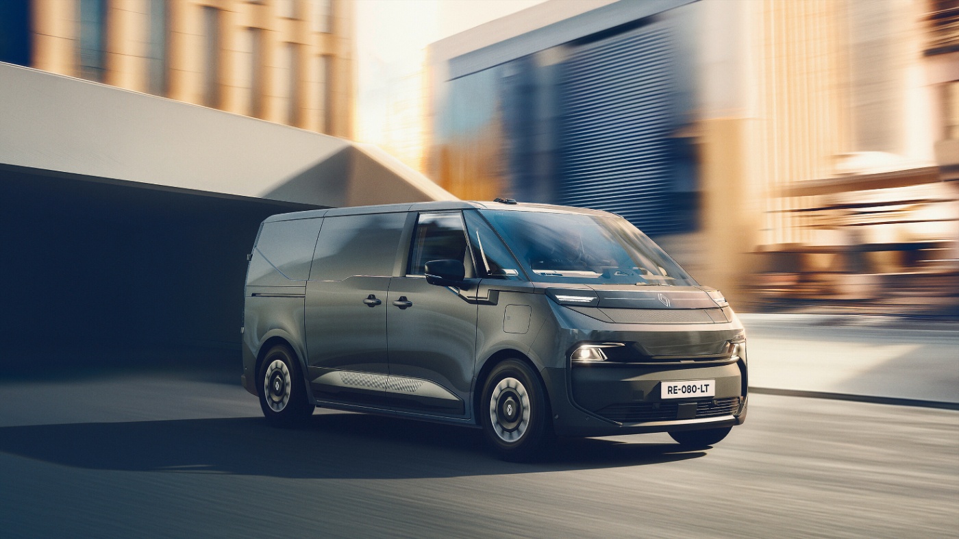 Modern electric Renault van driving through an urban area with blurred buildings.