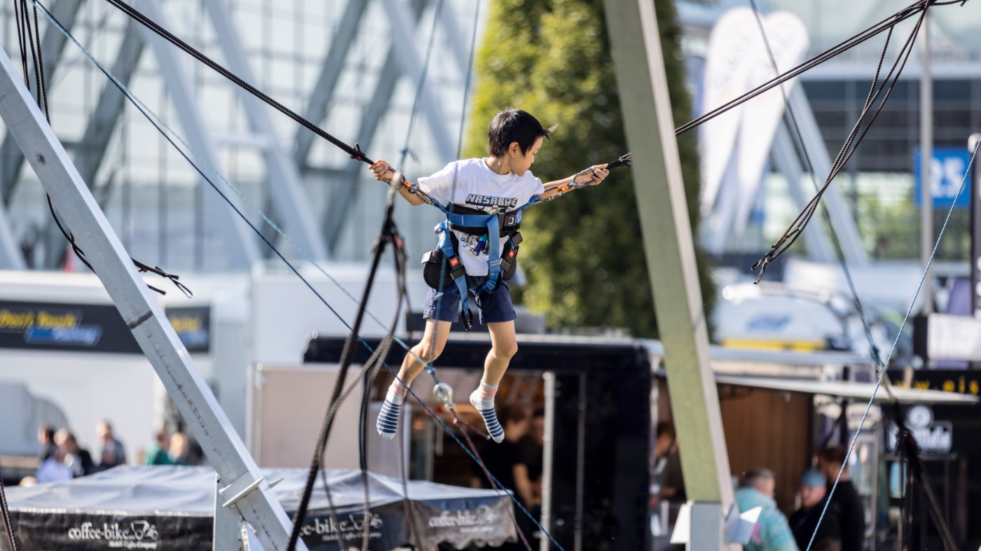 Kind nutzt eine Bungee-Trampolin-Attraktion bei einer Freiluftveranstaltung.